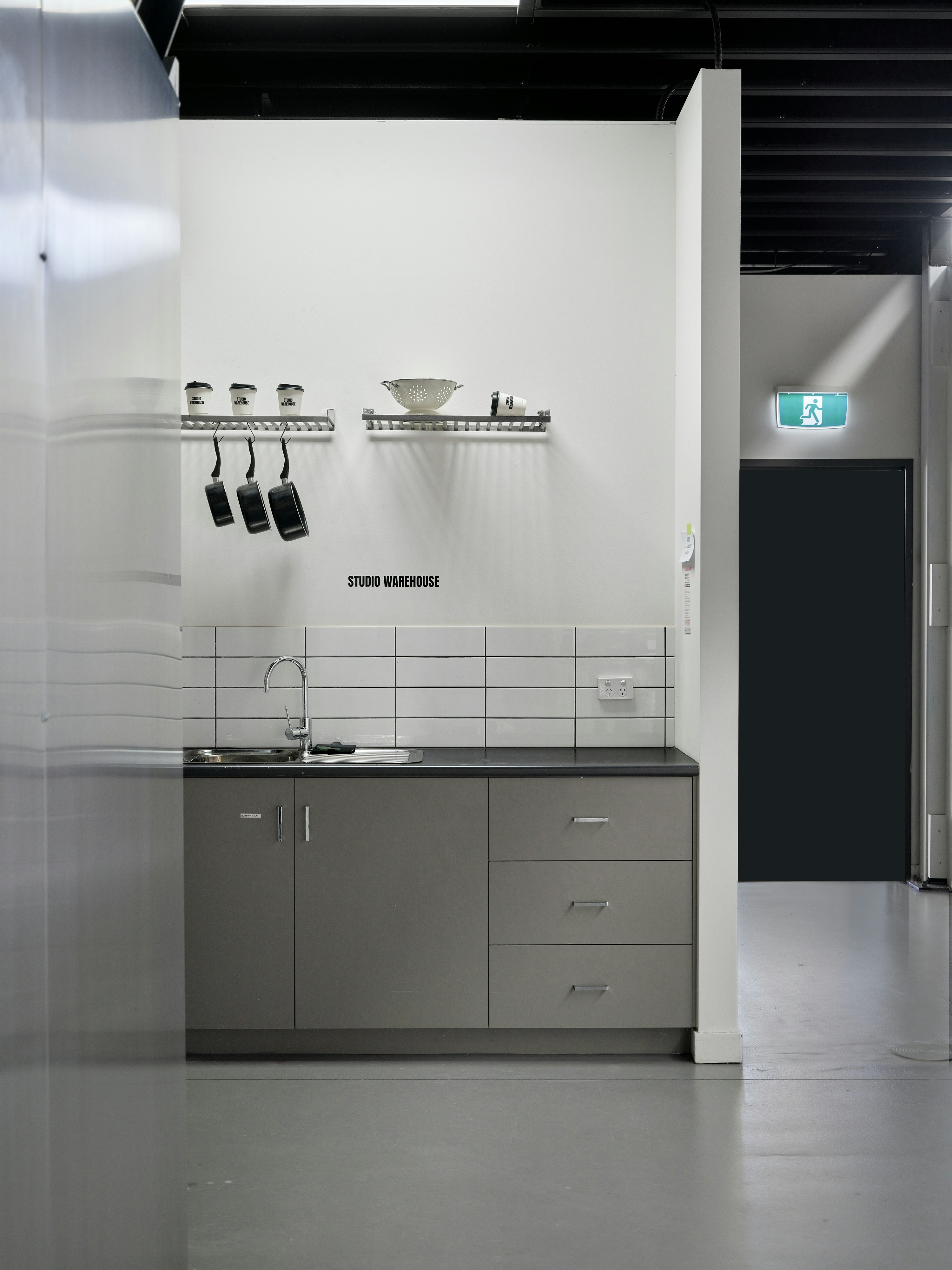 Wastafel dapur dengan kabinet abu-abu dan backsplash berubin putih di ruang kerja