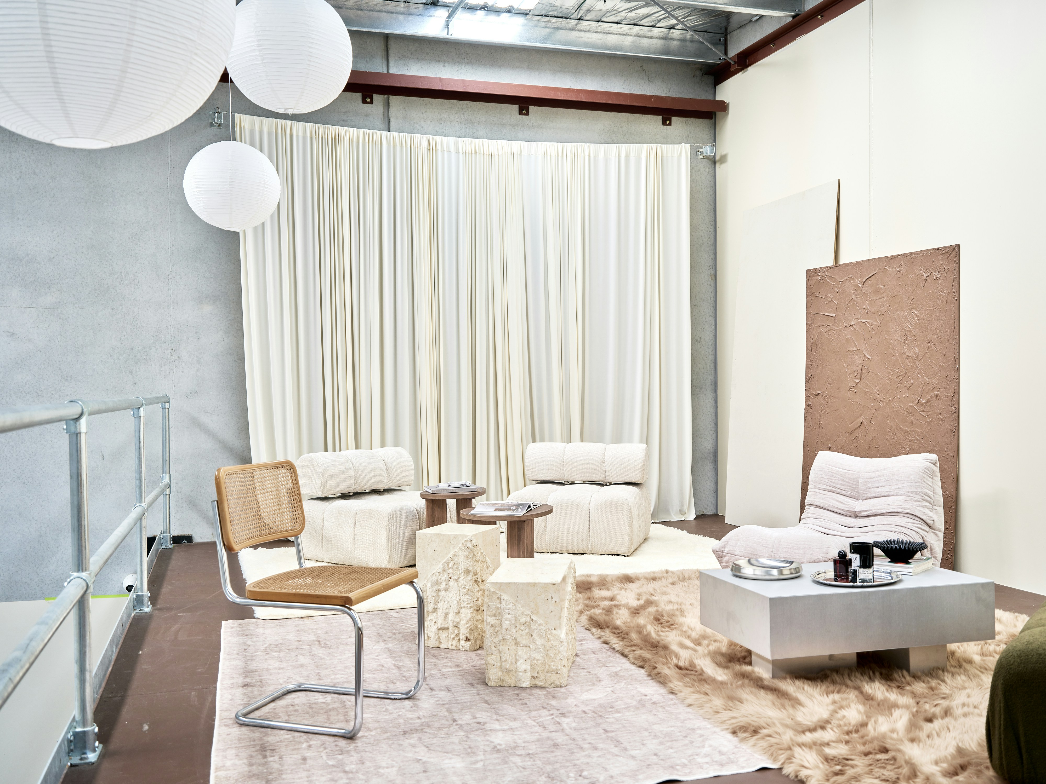 Perabotan lounge modern dengan kursi krem, meja batu, dan kursi tongkat di studio