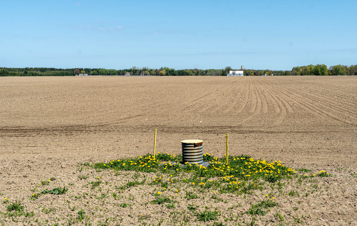 A capped water well head in a farm field