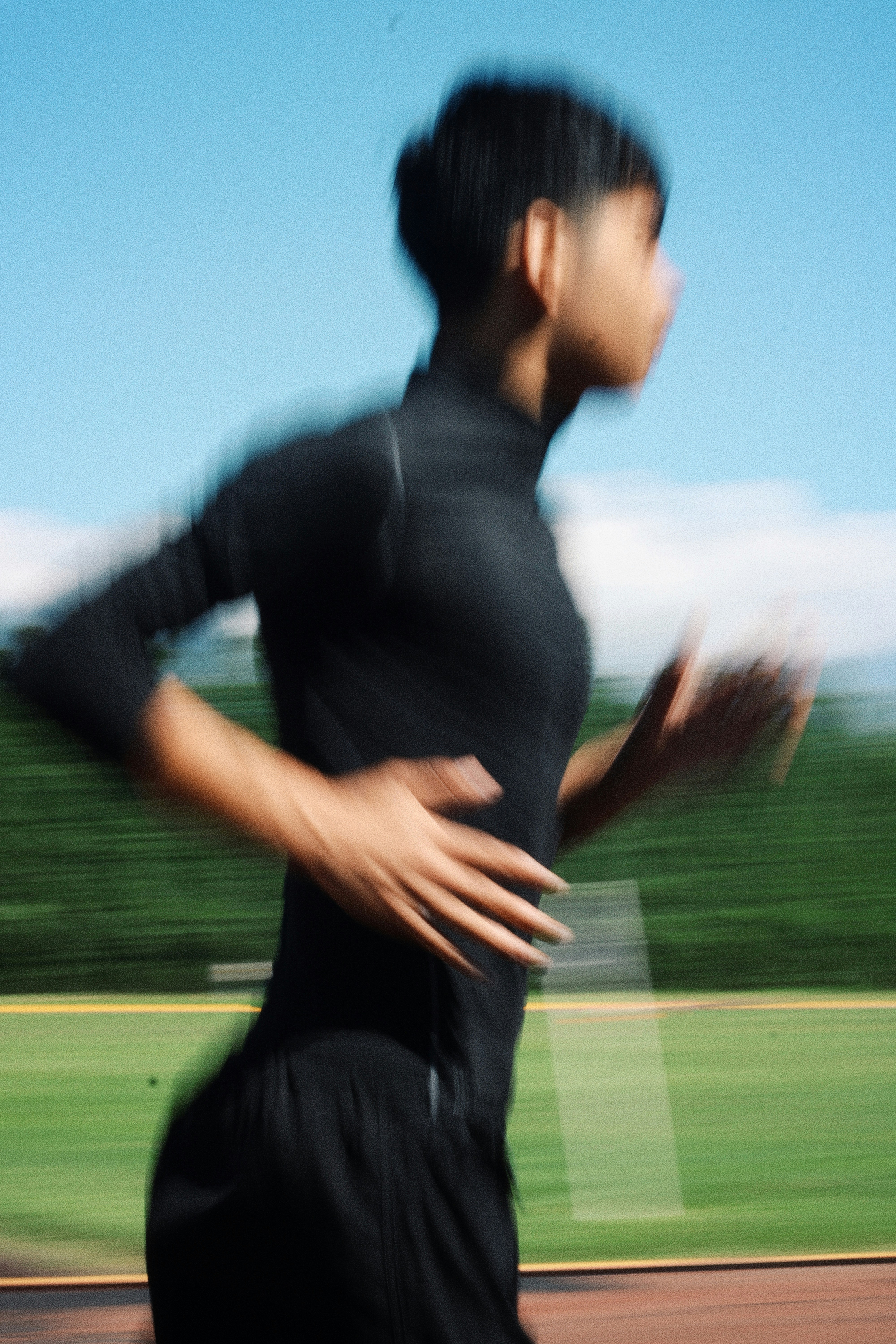 A person in a black athletic shirt running on a track