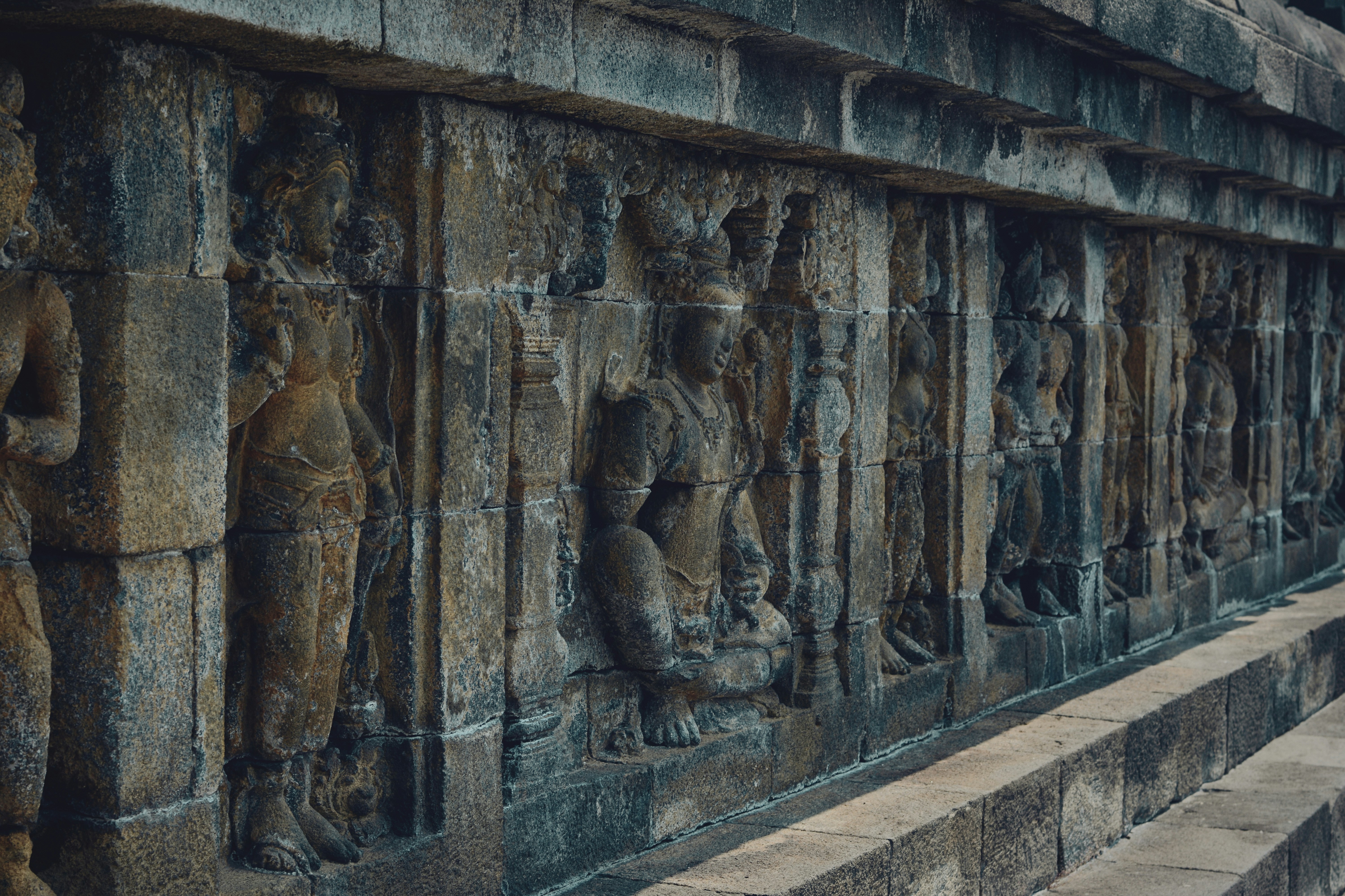 Stone relief carvings of figures on the walls of Borobudur Temple in Indonesia