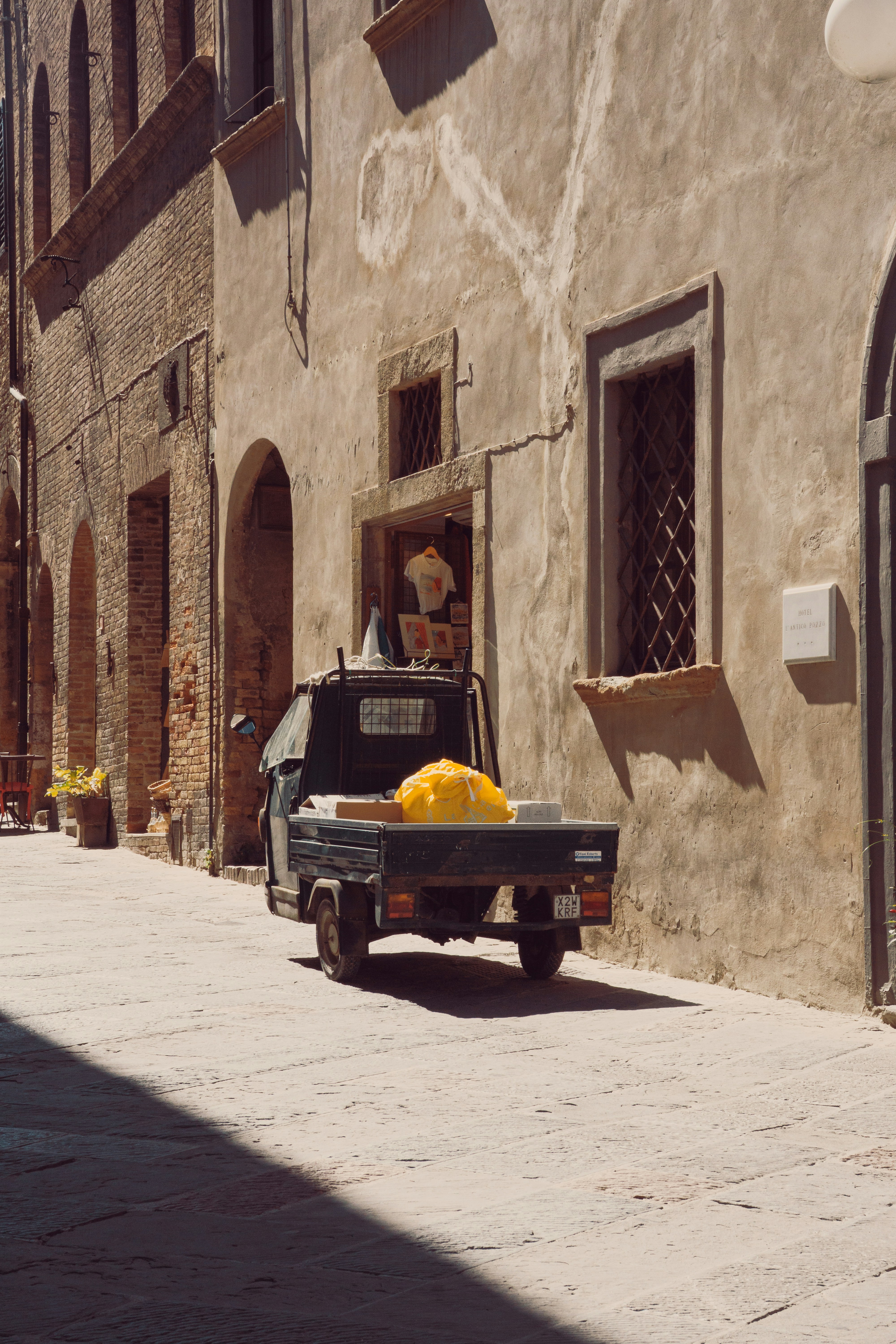 A small three-wheeled utility vehicle parked on a stone street in a historic town