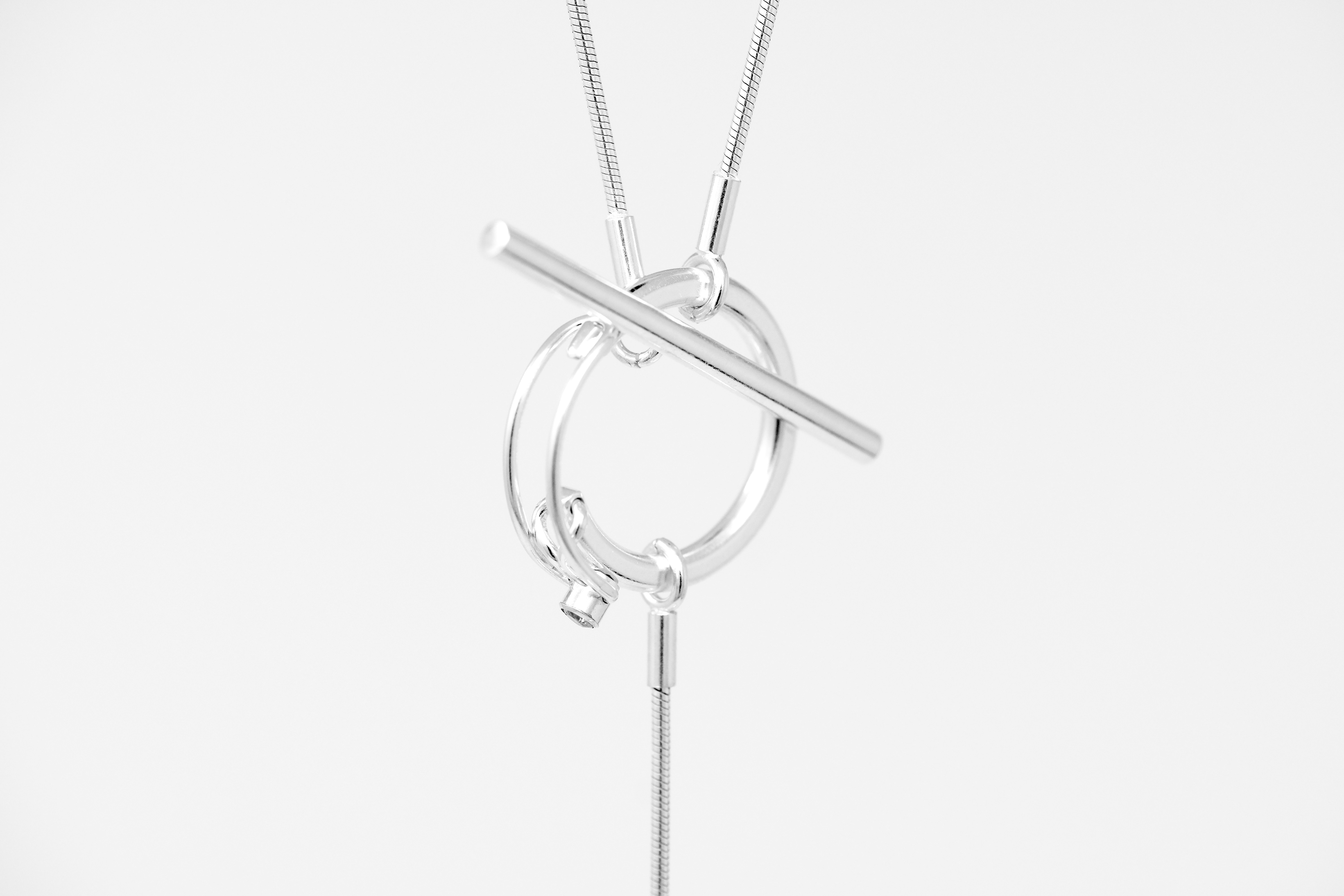 A silver toggle necklace with a circular ring and bar clasp