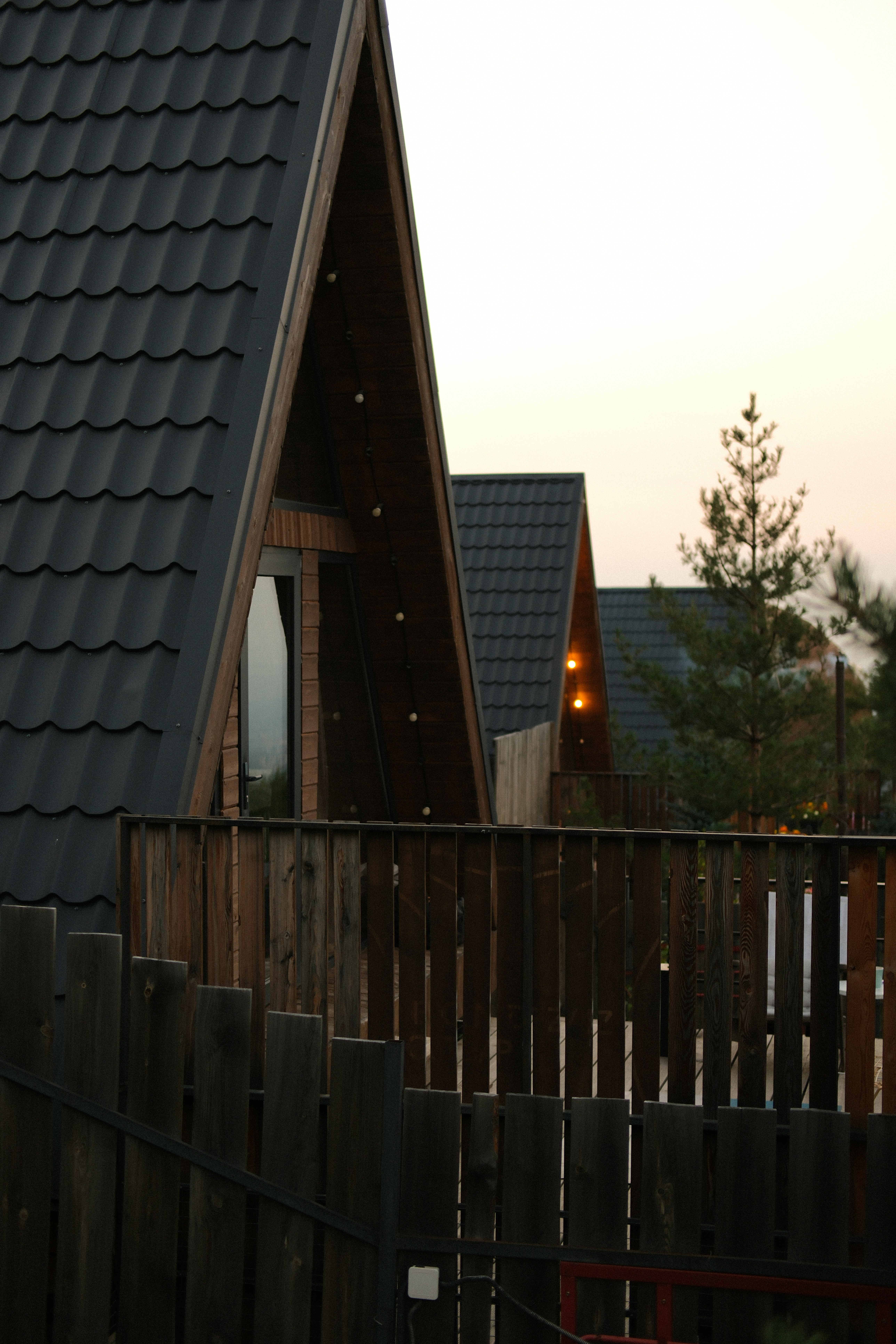A row of A-frame cabins with dark roofs and wooden balconies at dusk