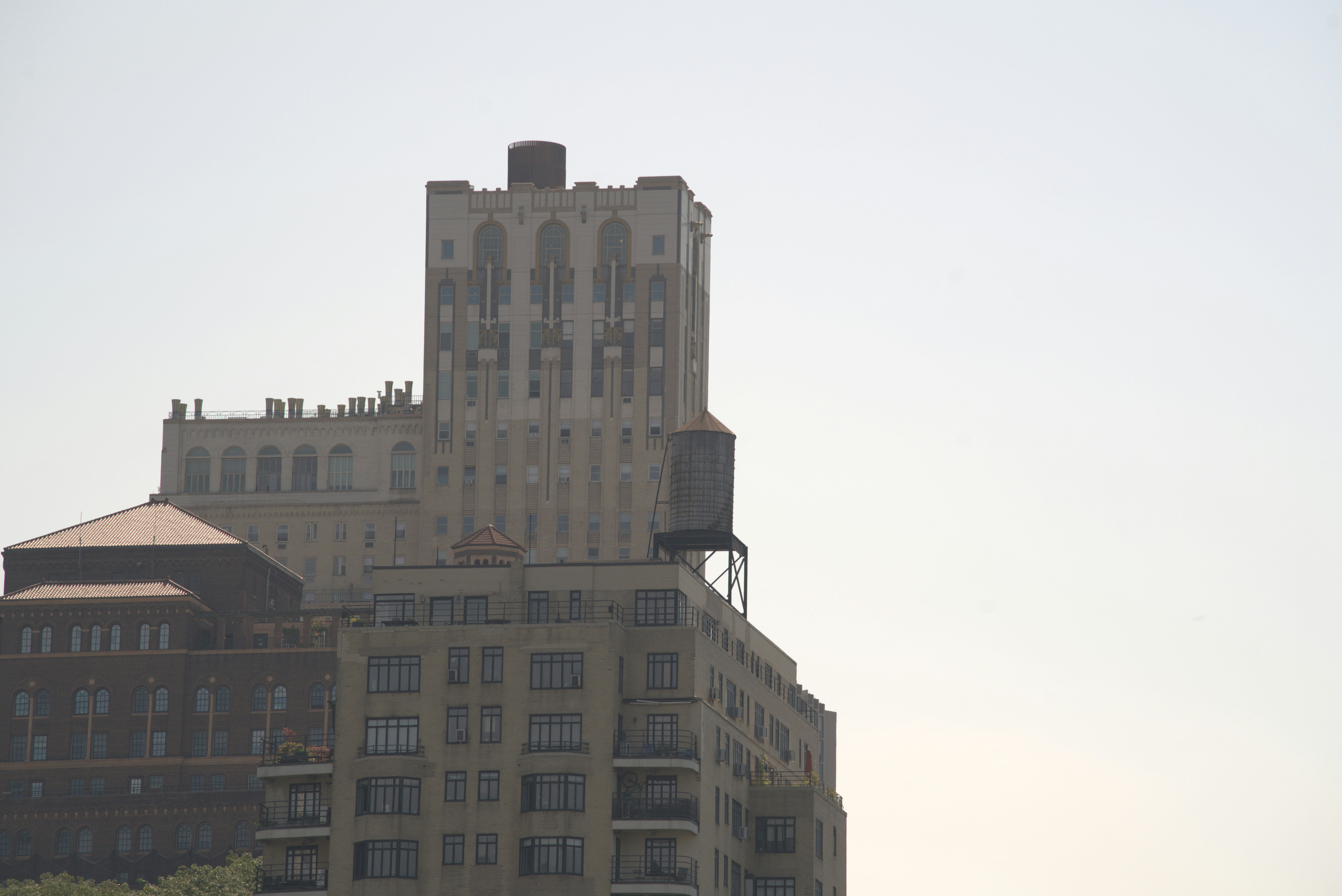 A tall apartment building with a water tower on the roof in New York