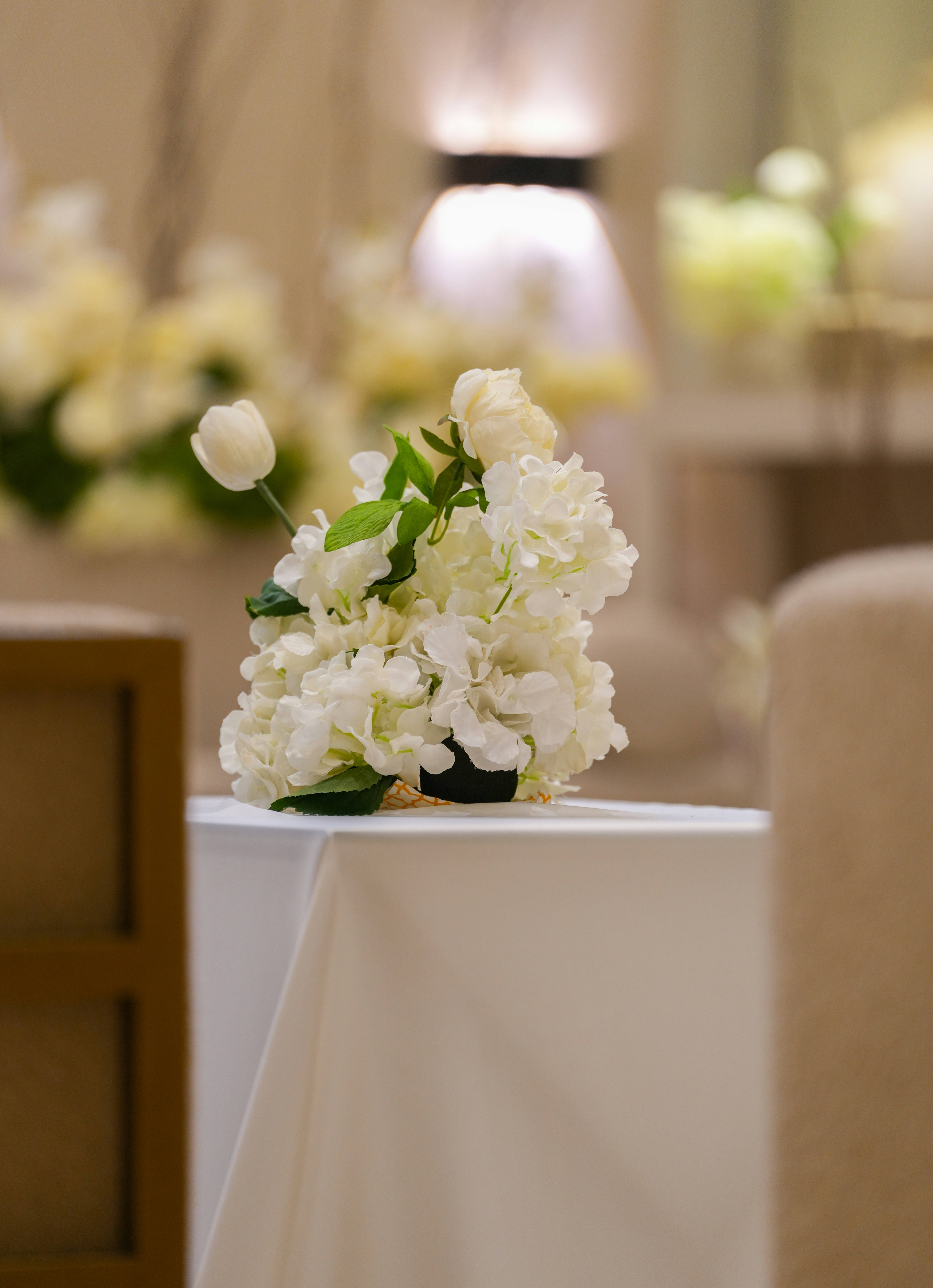 A bouquet of white flowers on a table covered with a white cloth.