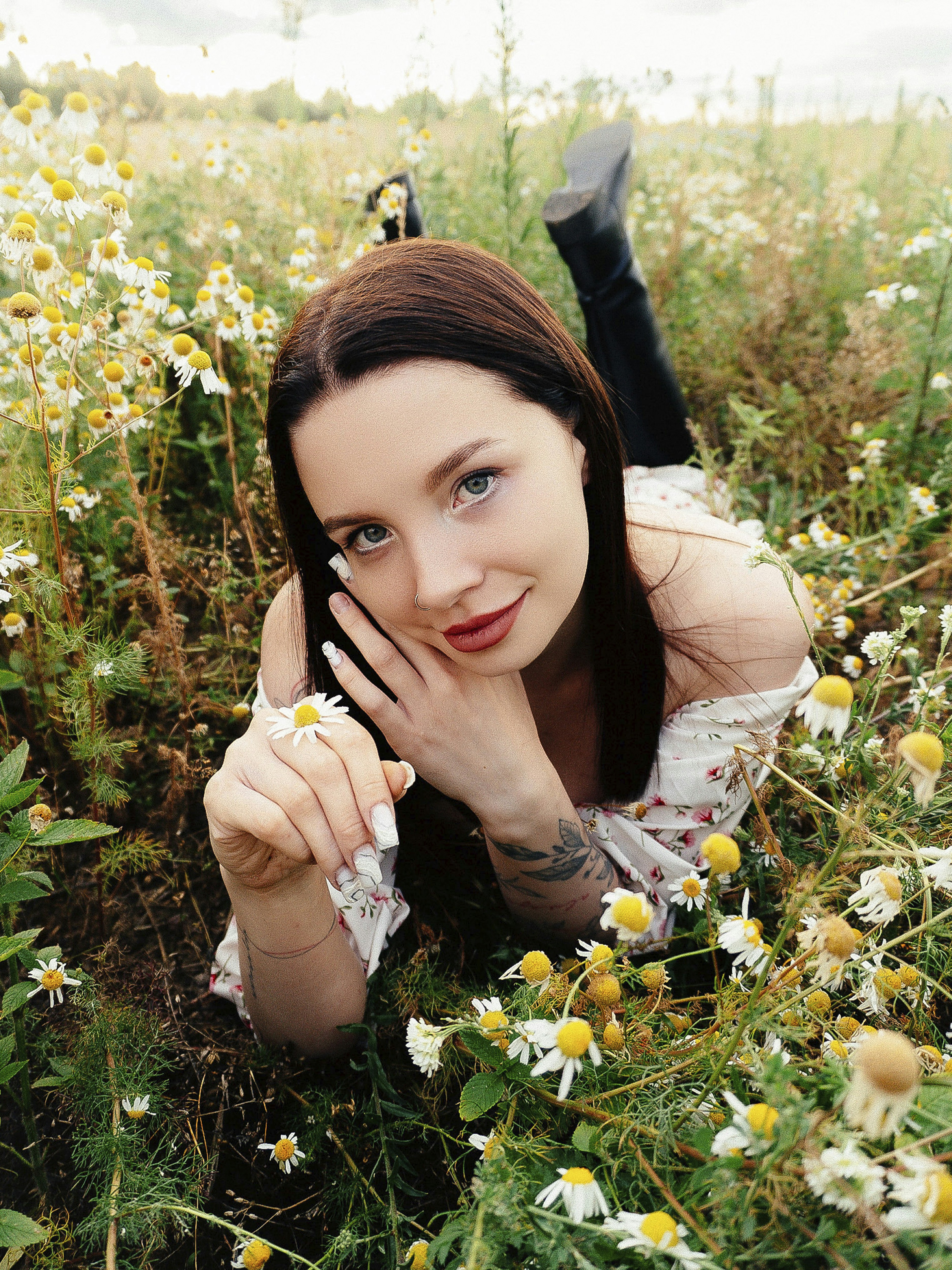 Dark-haired woman lying in a field of chamomile flowers