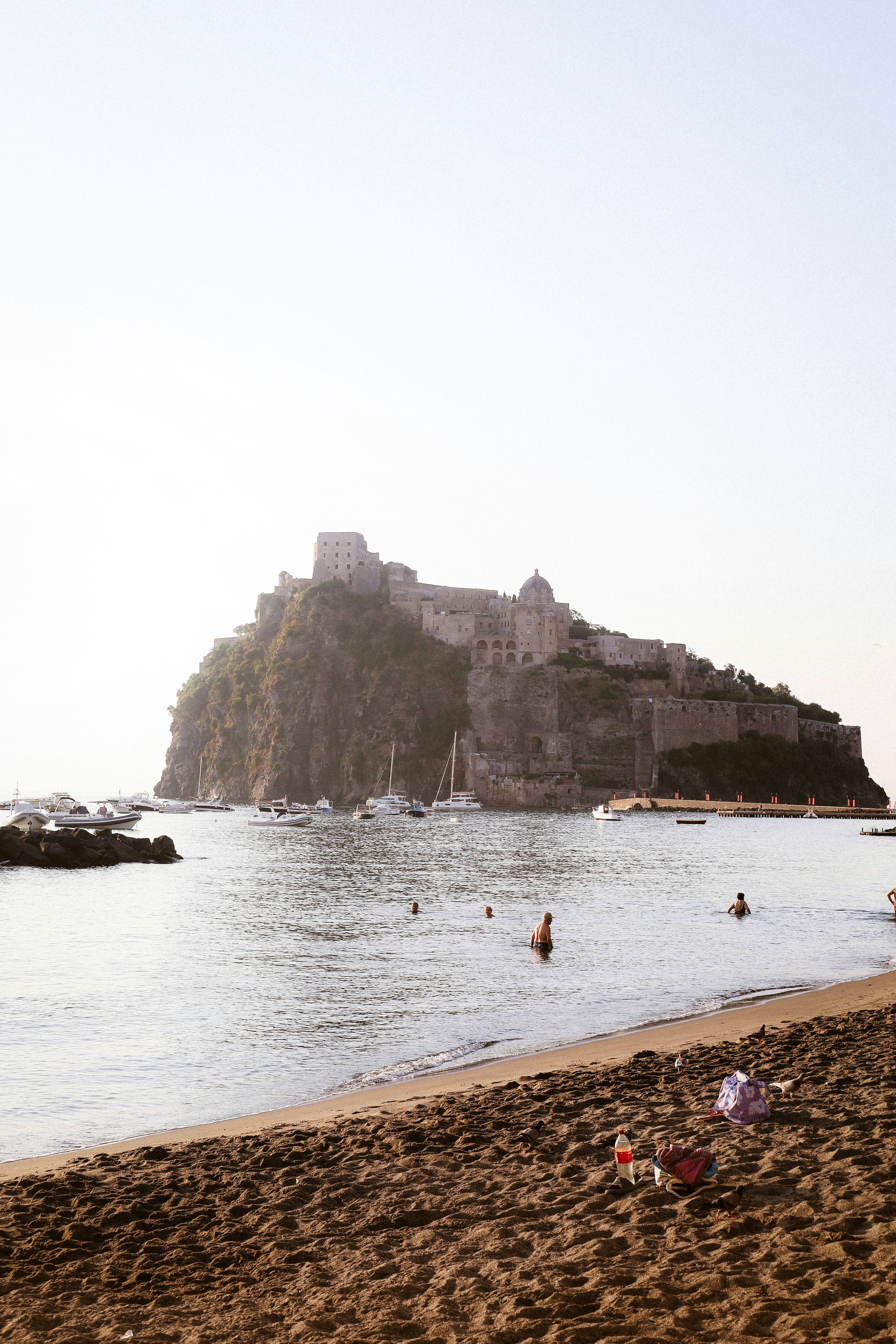 People swimming in the sea before the Castello Aragonese on Ischia, Italy