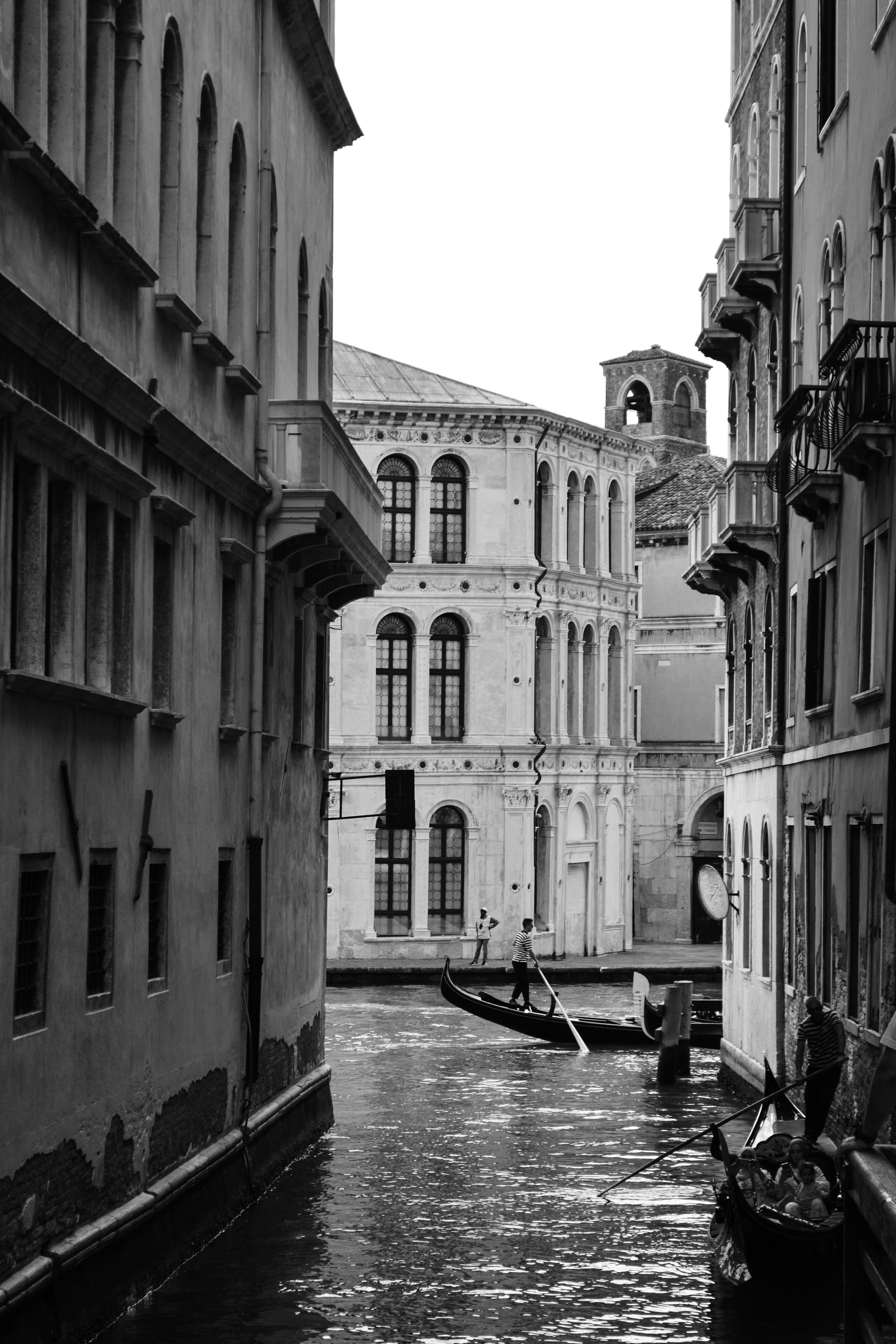 A gondolier rowing a gondola through a narrow canal in Venice, Italy