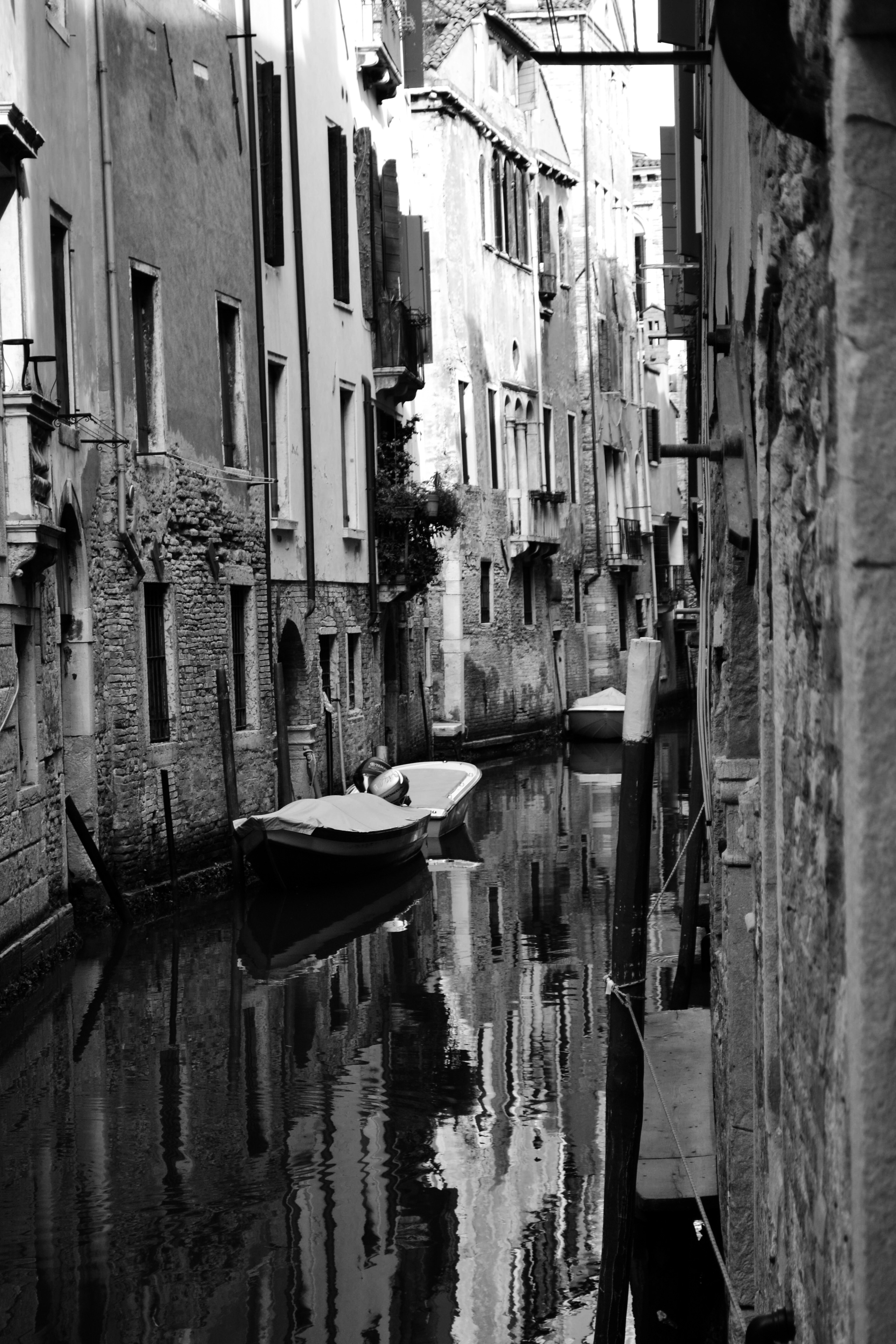 Boats moored in a narrow canal between old brick buildings in Venice, Italy