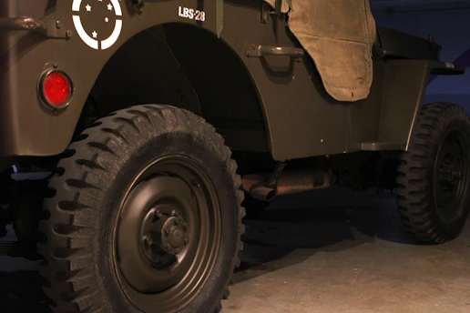 An olive drab military vehicle with large treaded tires and a canvas door