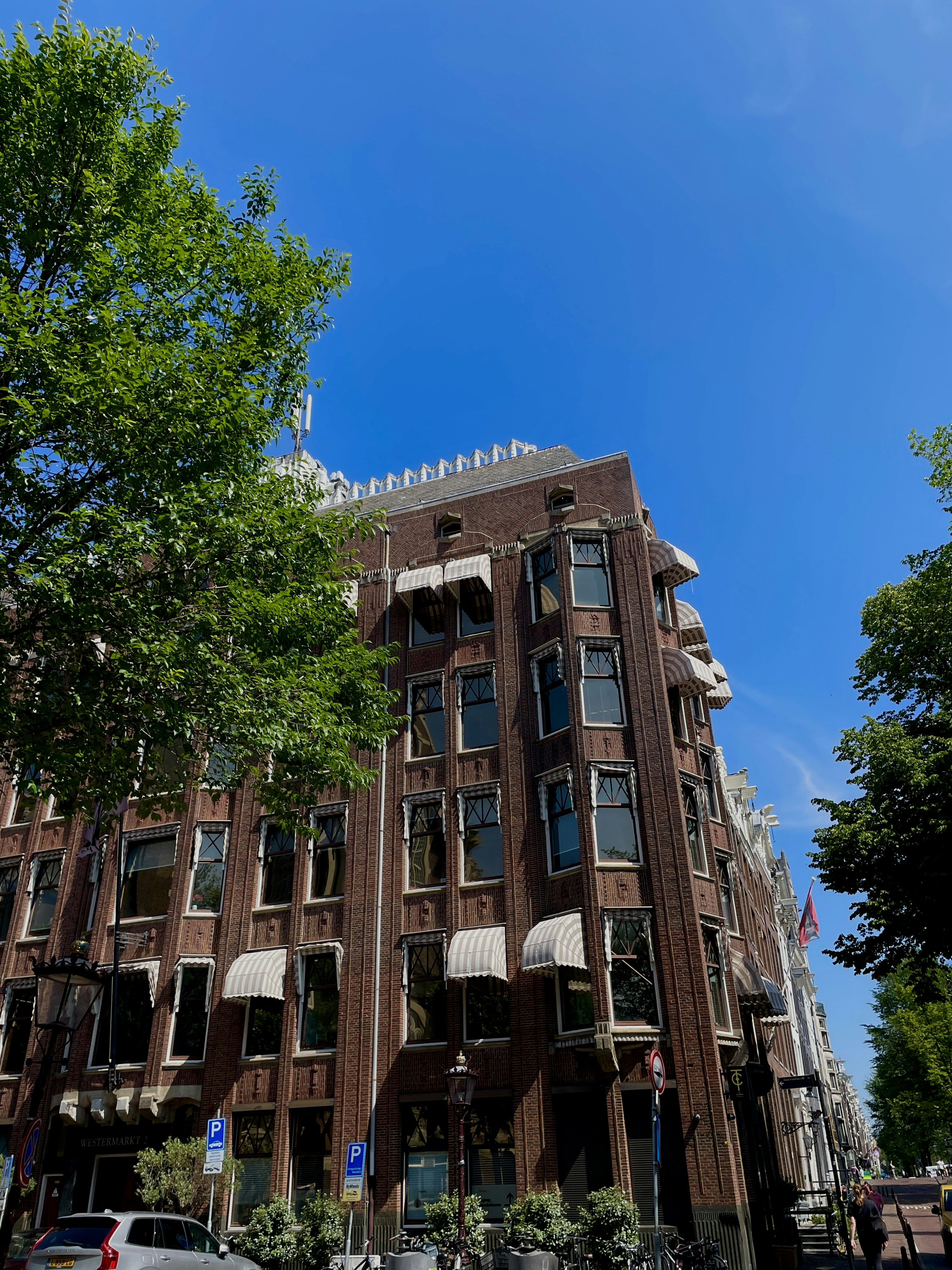 A brick building with striped awnings under a clear blue sky in Amsterdam