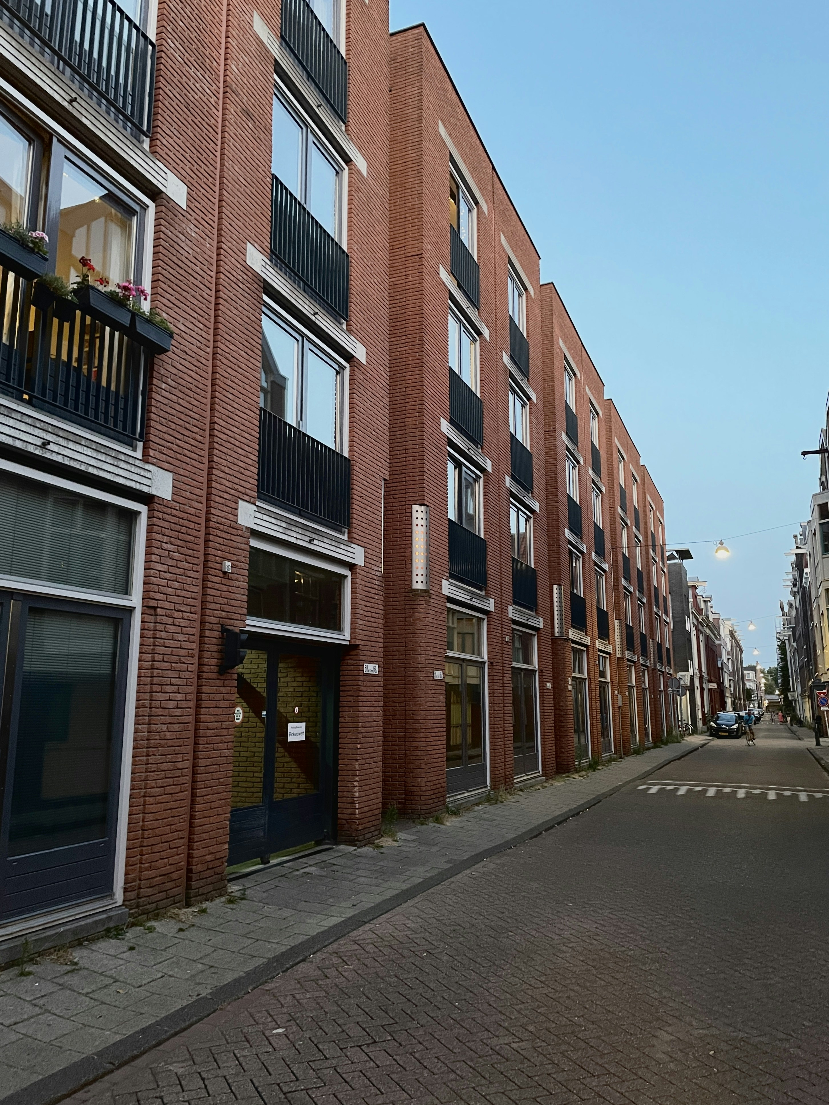 A narrow street lined with modern red brick apartment buildings and black balconies