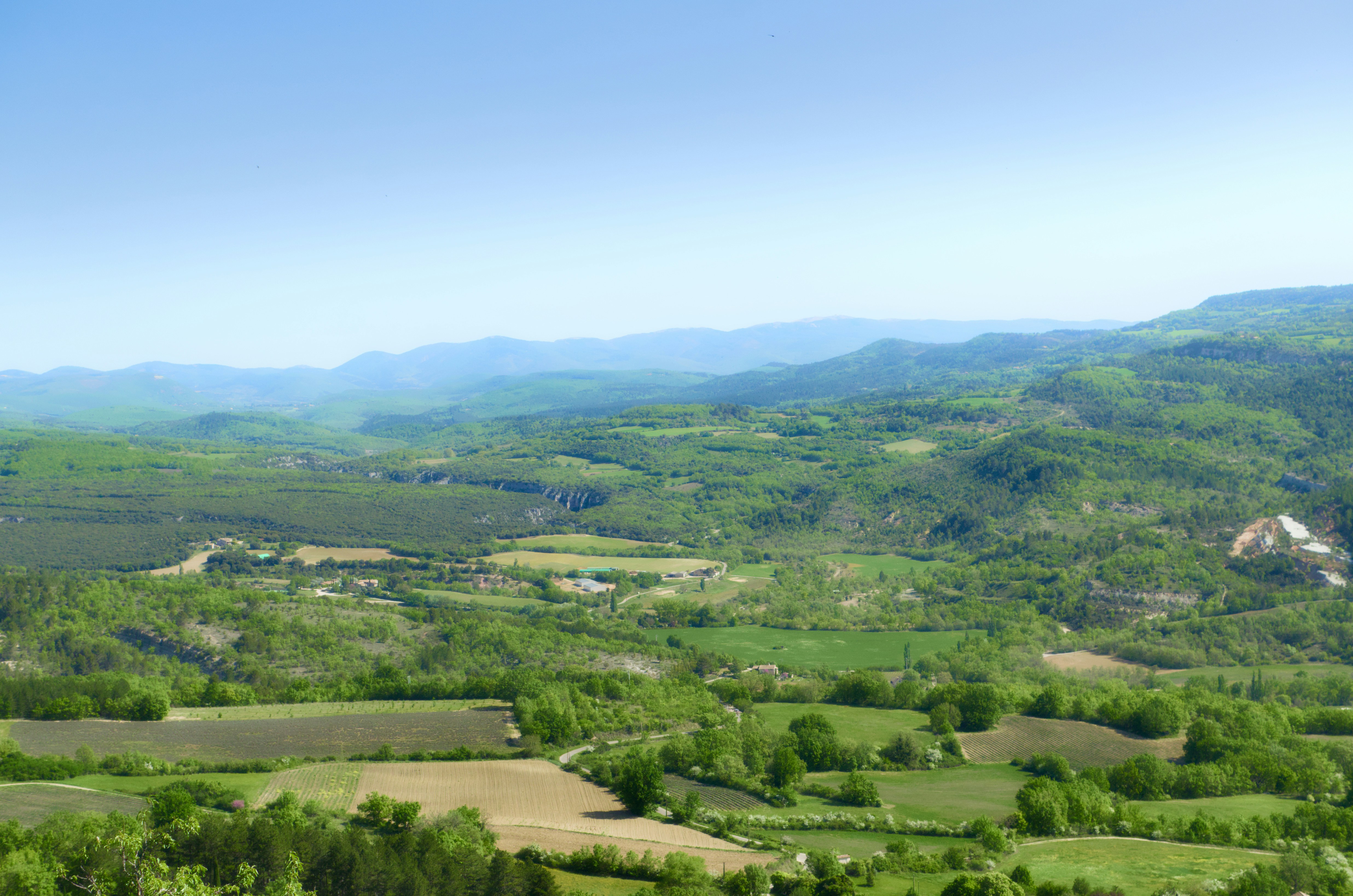A vast green valley with rolling hills and agricultural fields under a clear sky