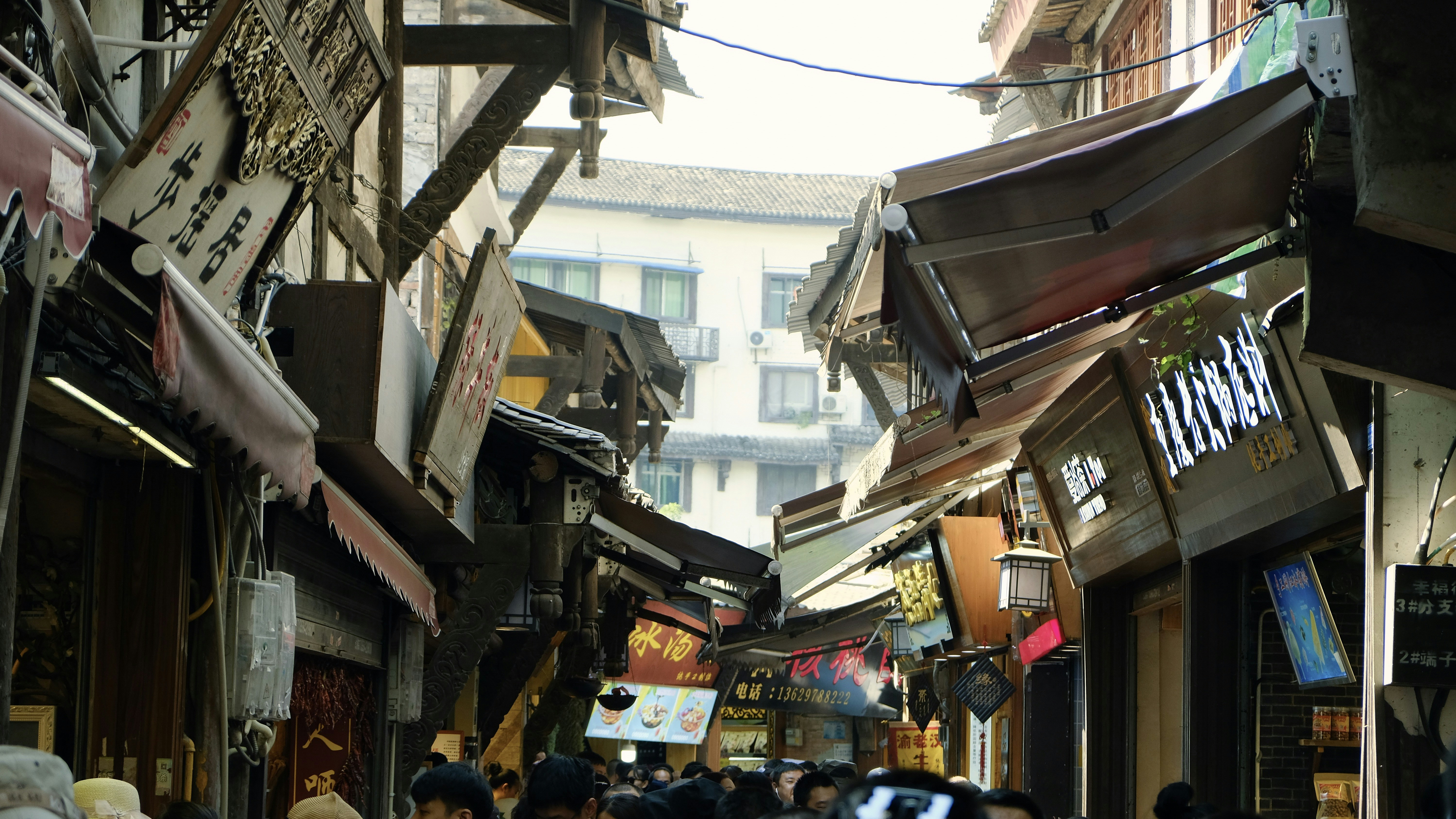 A crowded narrow street lined with traditional wooden buildings and shopfronts in Lijiang