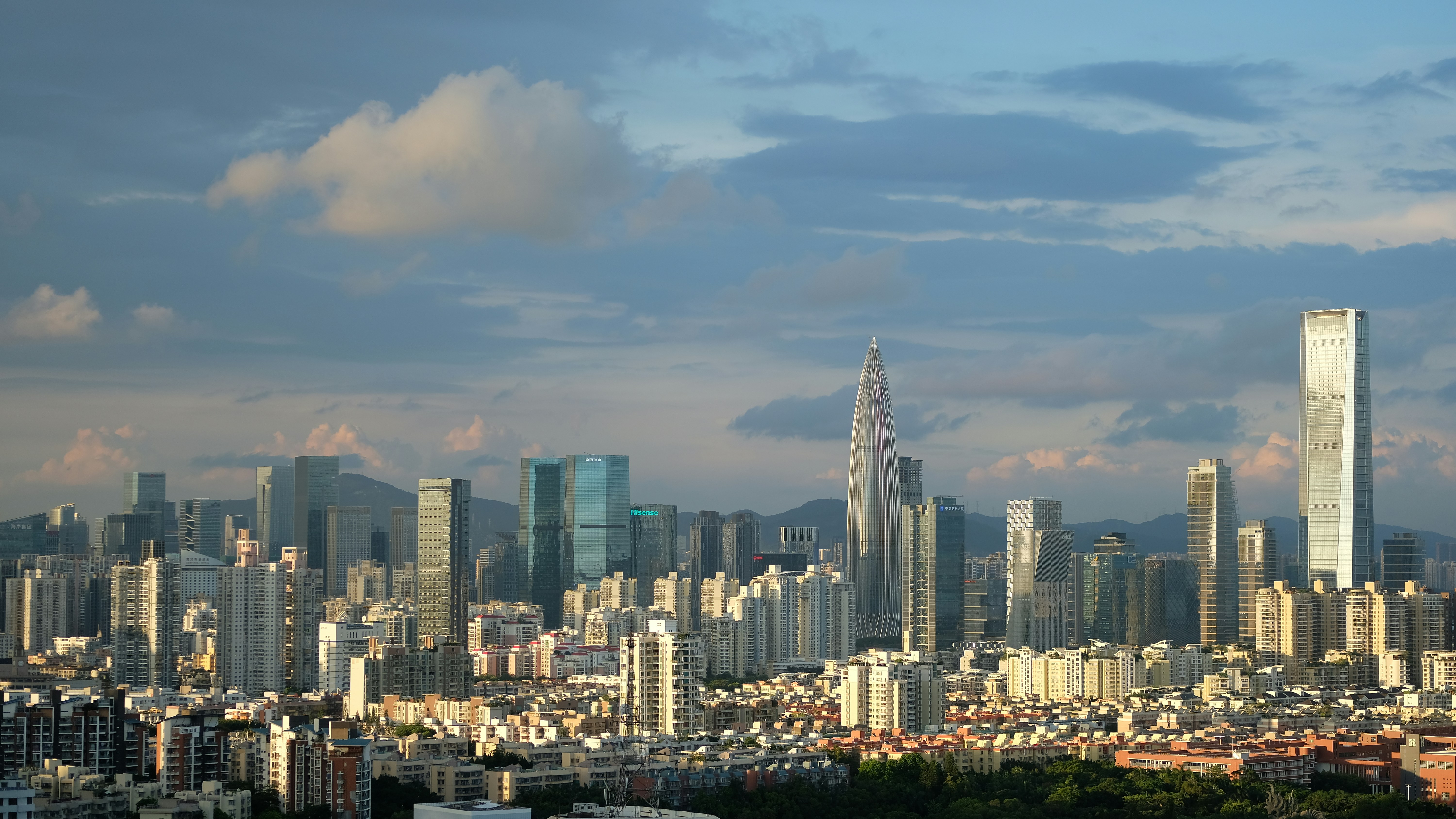 A dense city skyline with modern skyscrapers under a blue sky with clouds