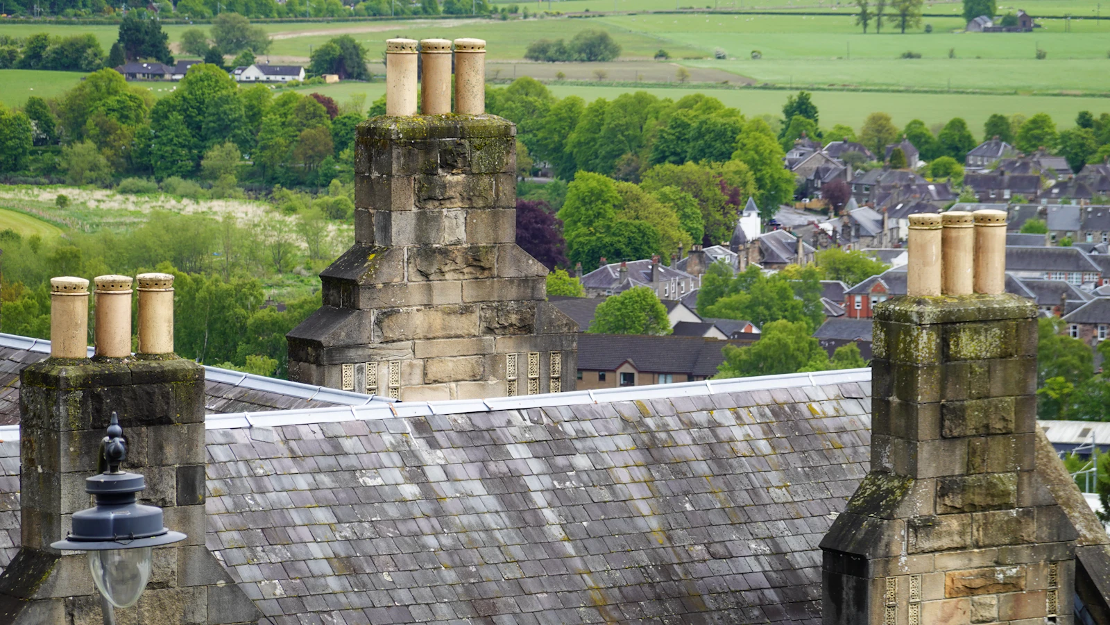 Slate roof with stone chimney stacks overlooking a British town and fields