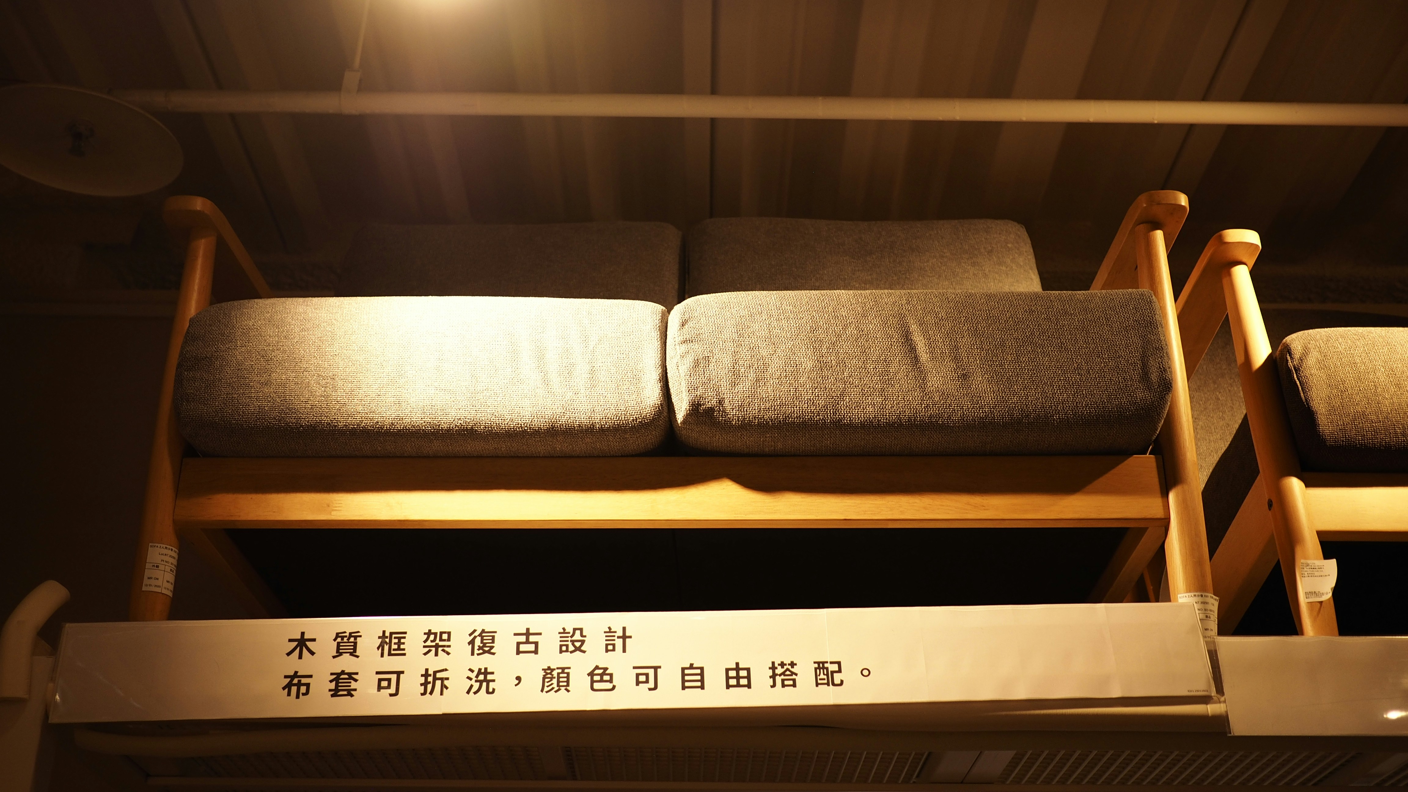 A grey fabric sofa with a wooden frame under warm overhead lighting