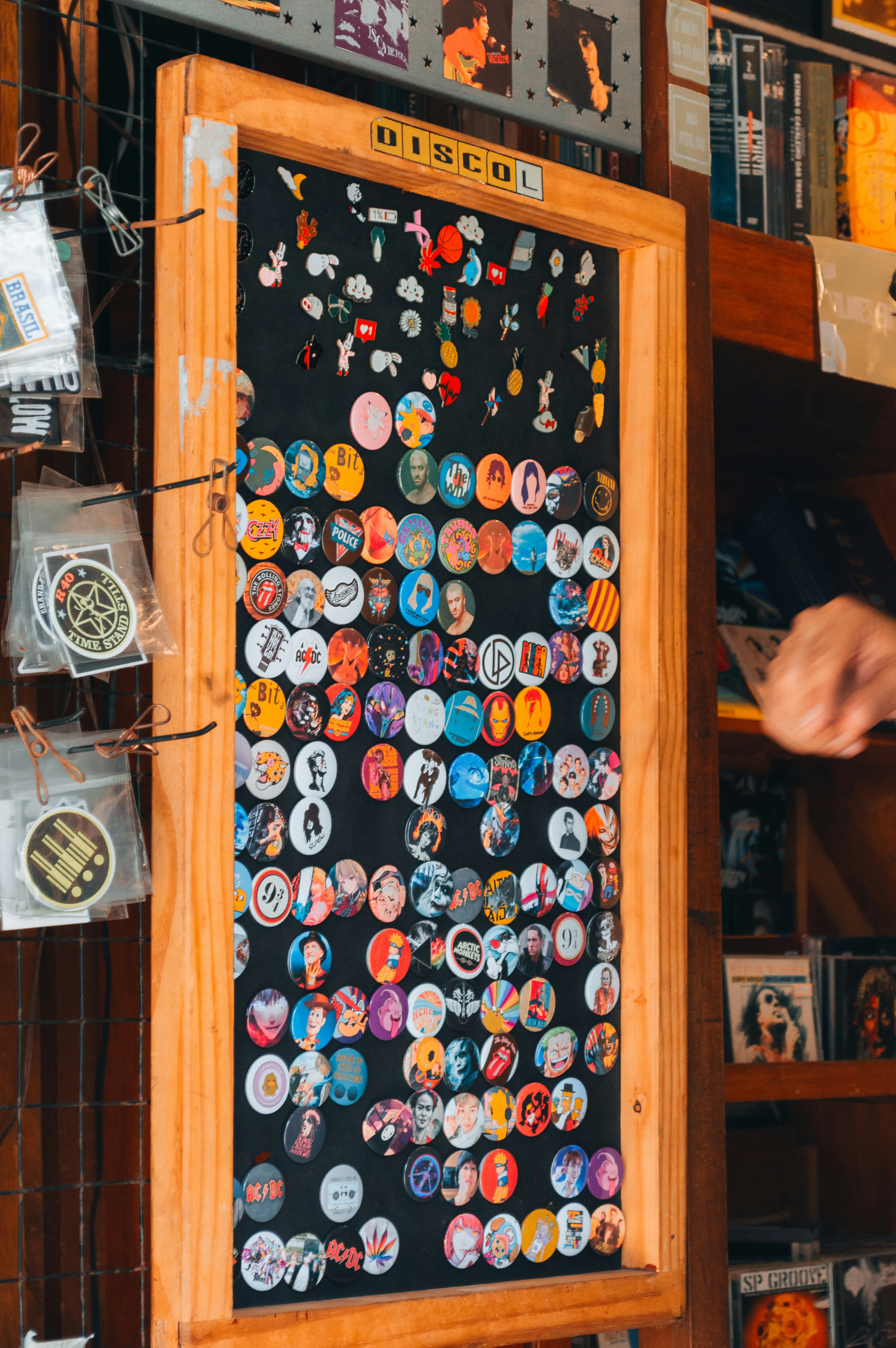 A wooden display board covered in numerous colorful circular pinback buttons and badges