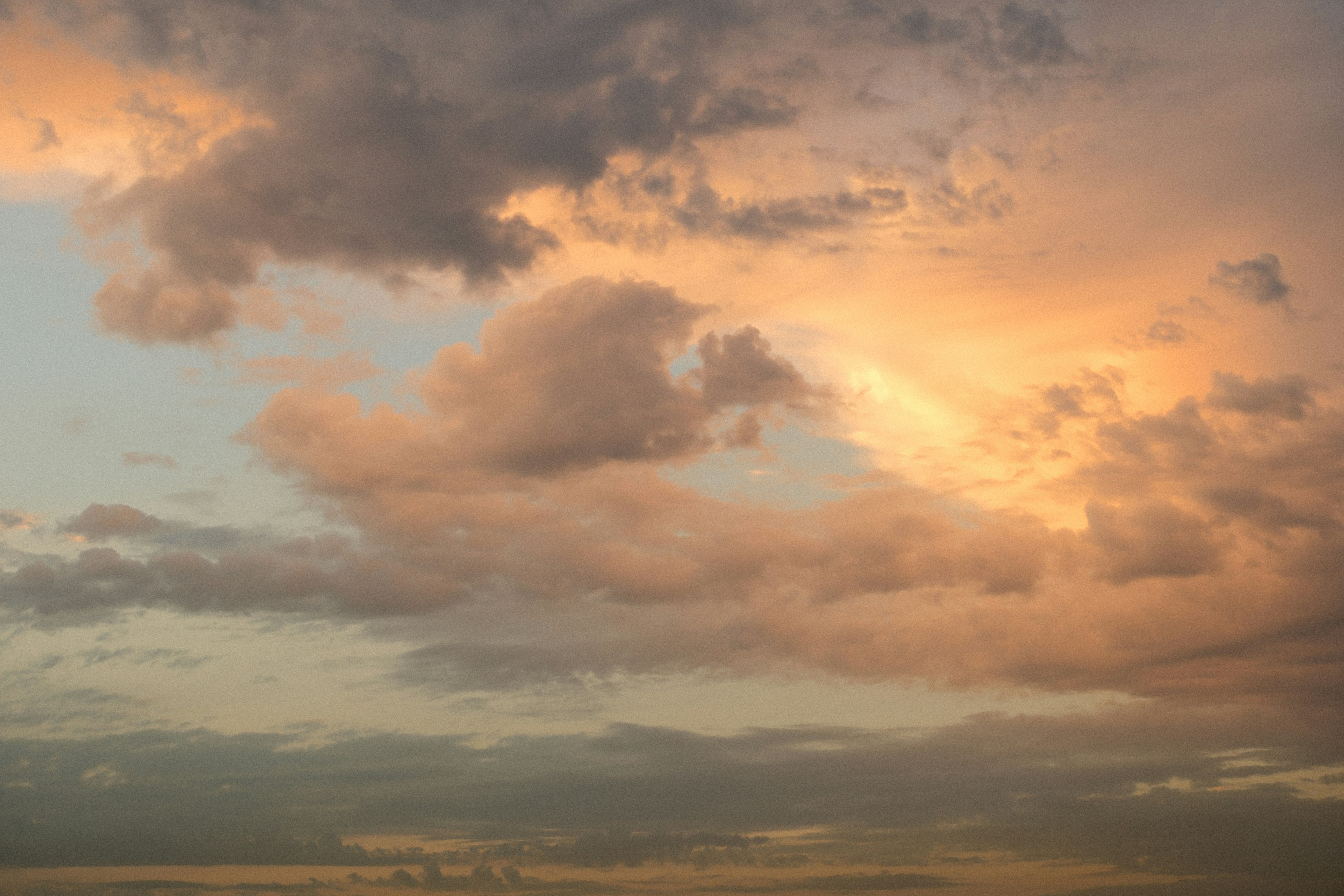 Clouds illuminated by warm orange light in a soft sky