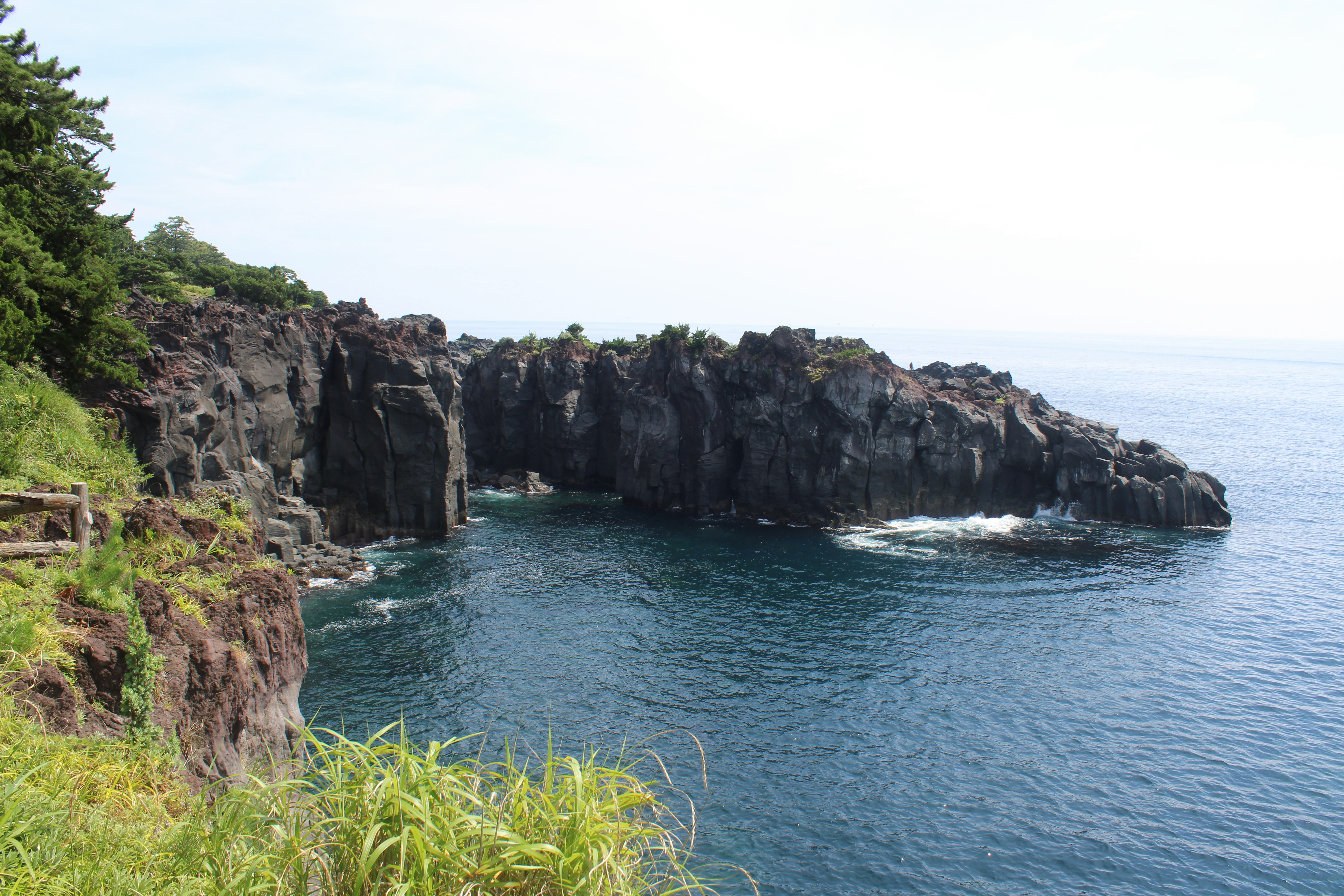 Dark volcanic rock cliffs rising above deep blue ocean water