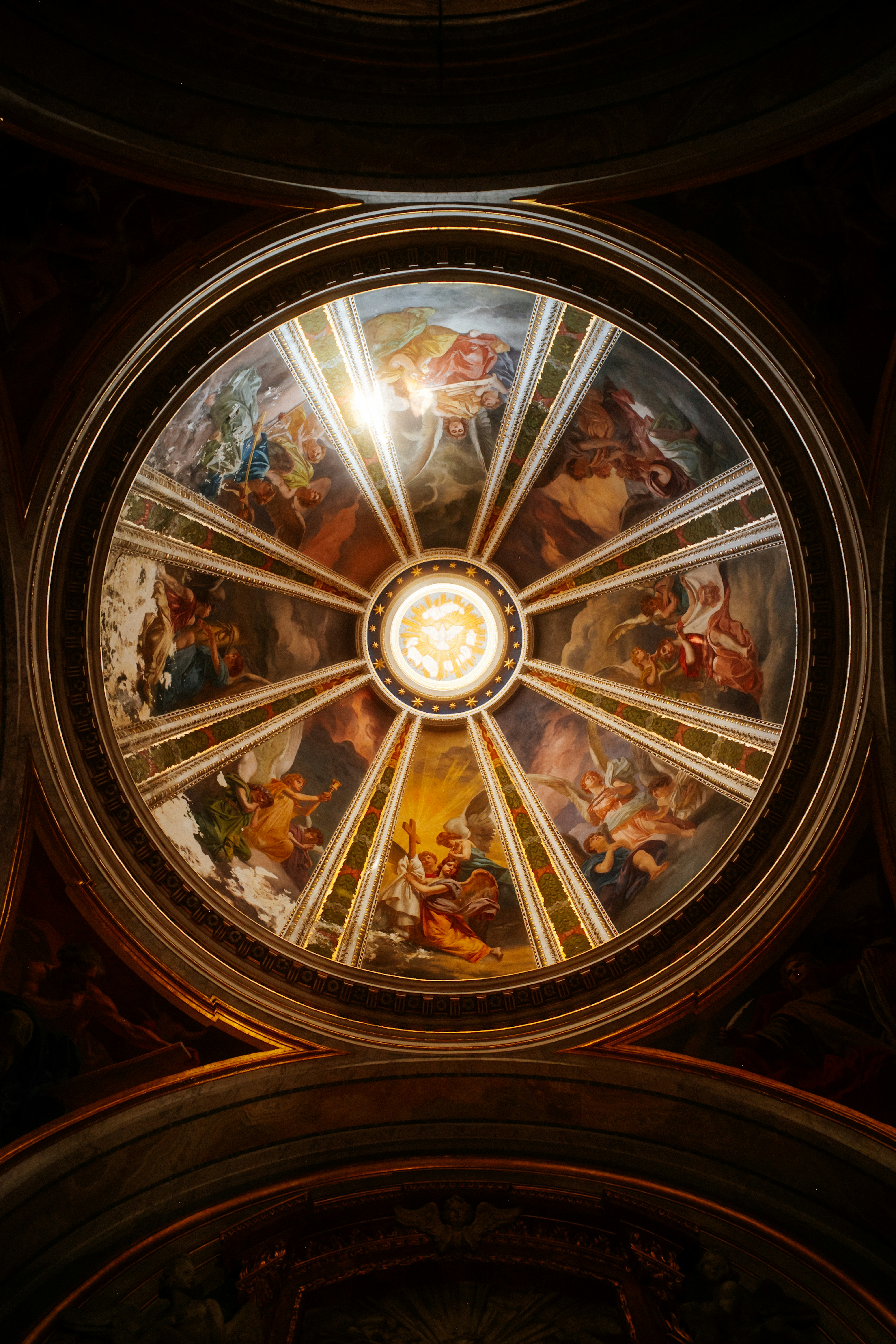 A circular dome ceiling featuring religious frescoes and a central illuminated lantern.