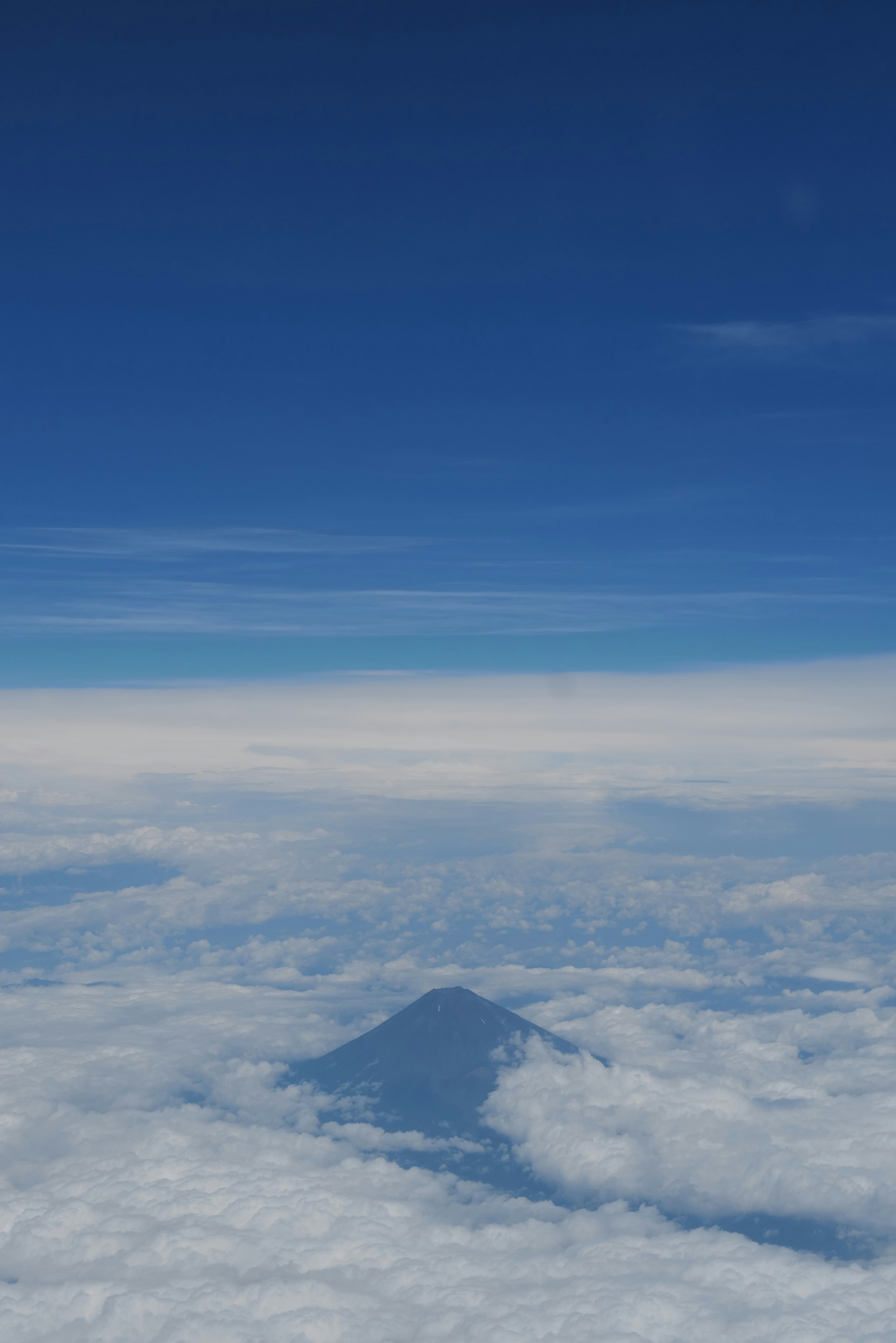 The peak of Mount Fuji rising above a thick layer of white clouds