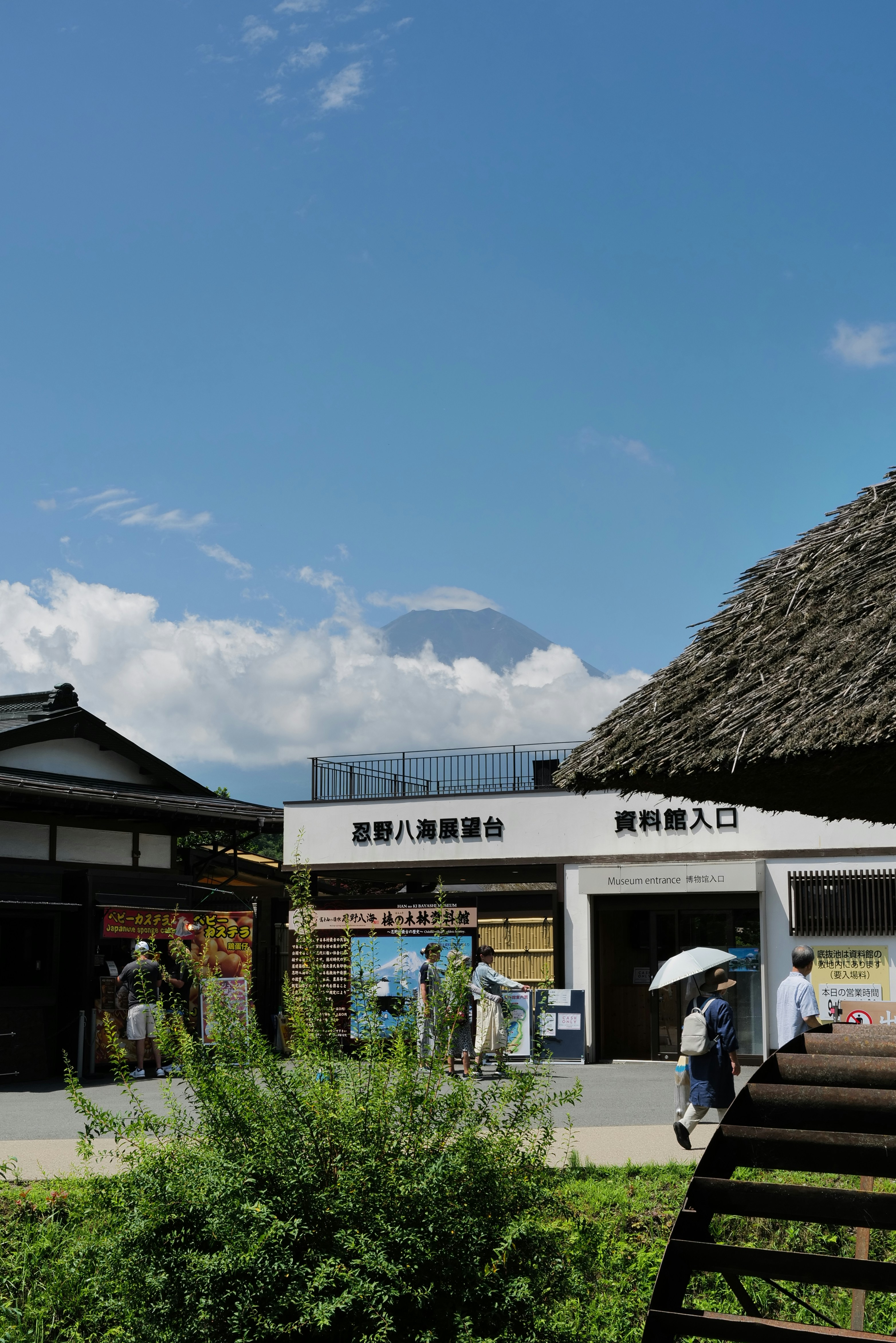 People walking near a museum entrance with Mount Fuji visible in the distance