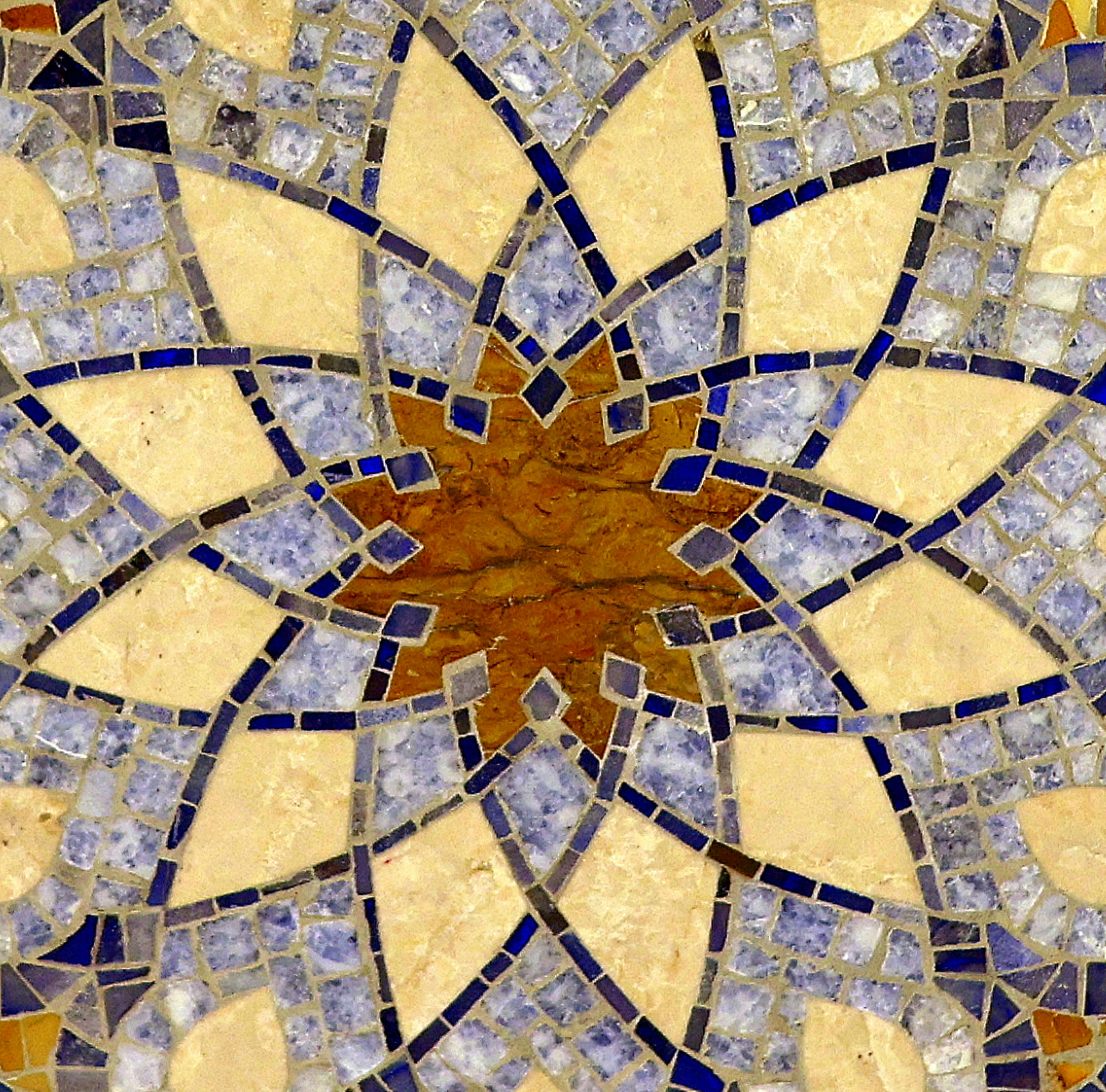 A geometric mosaic pattern with blue and beige stone tiles in a star shape.