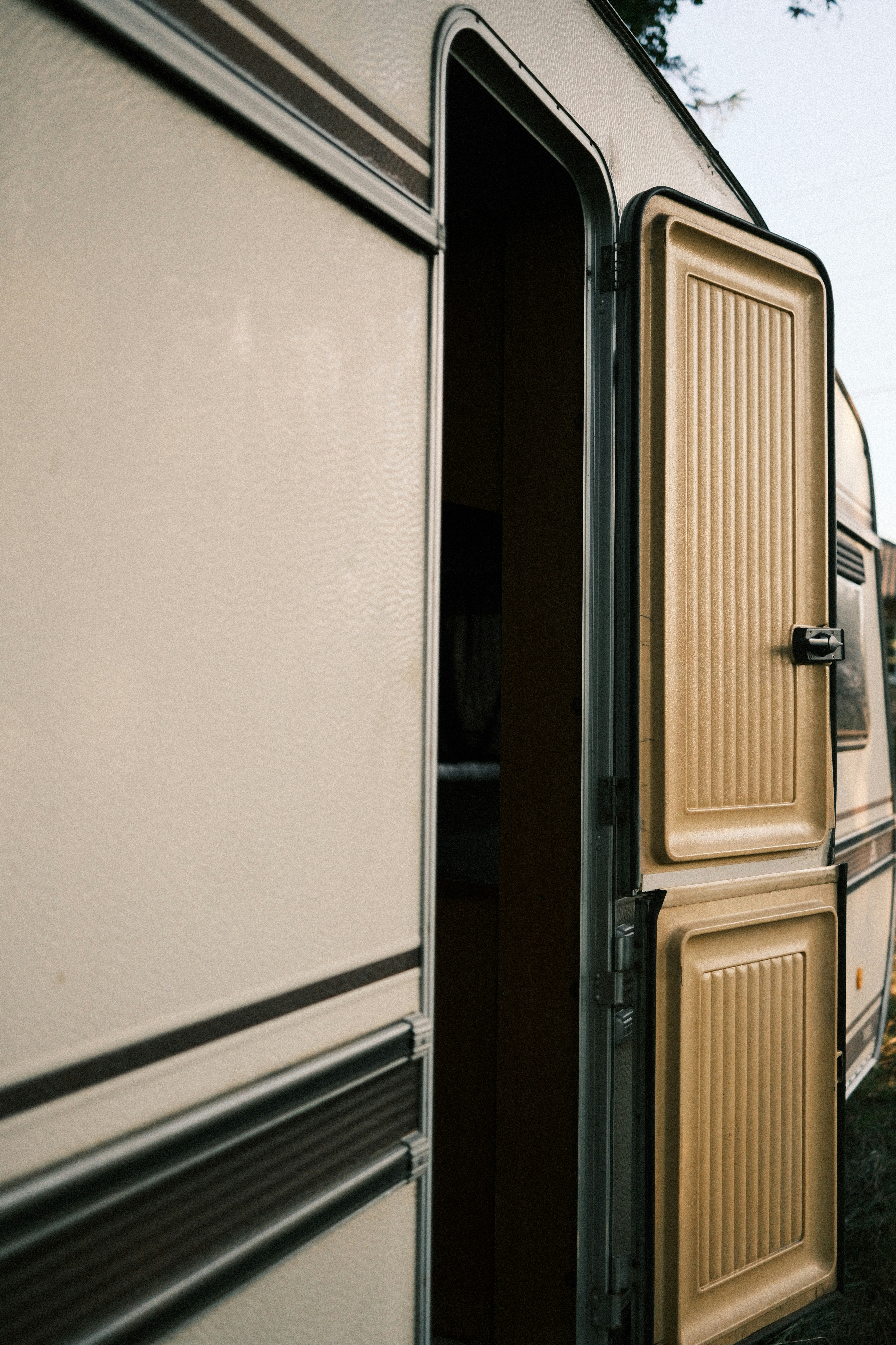 An open door on a vintage cream-colored travel trailer