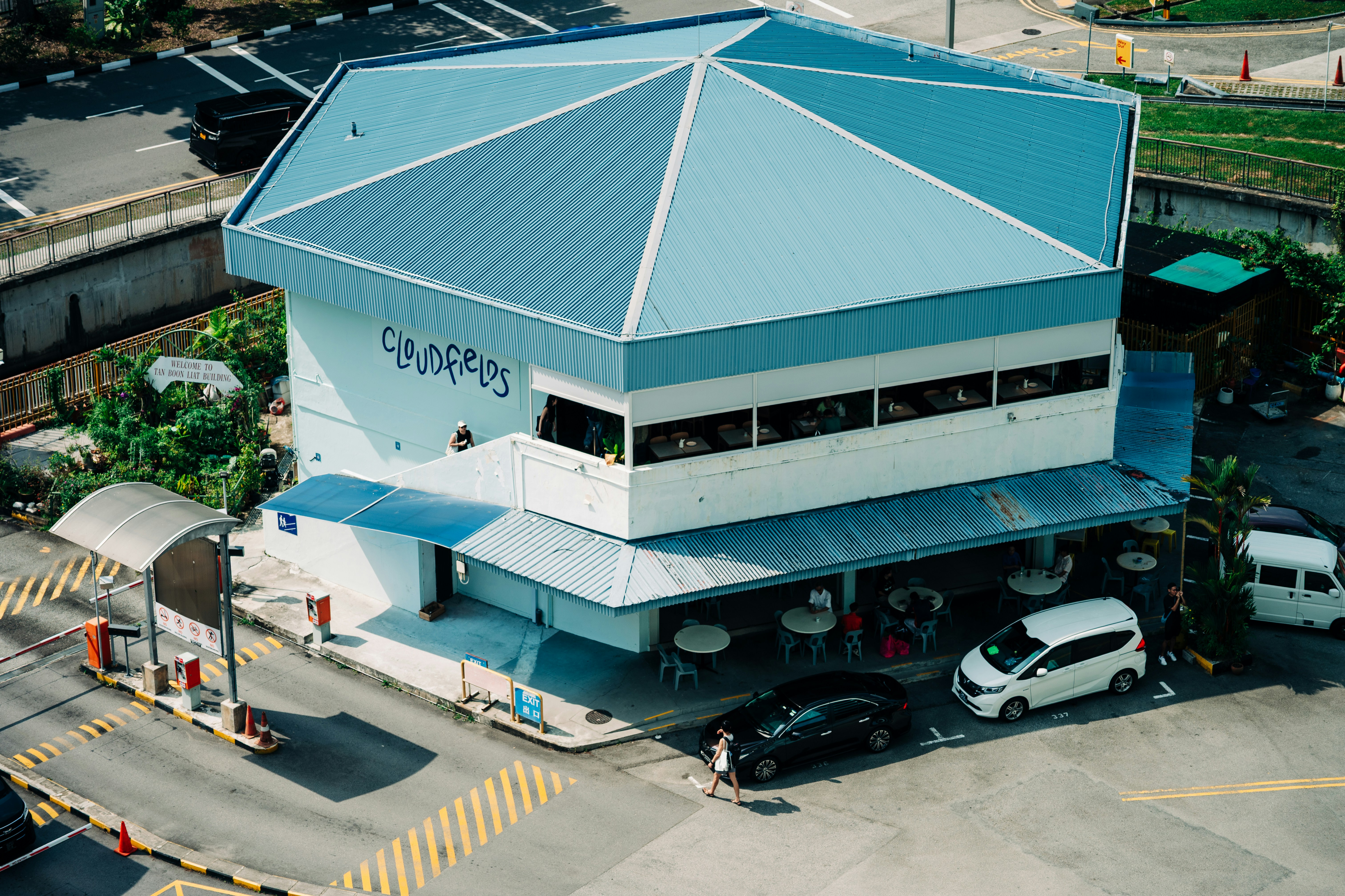 An aerial view of a building with a blue roof and outdoor seating