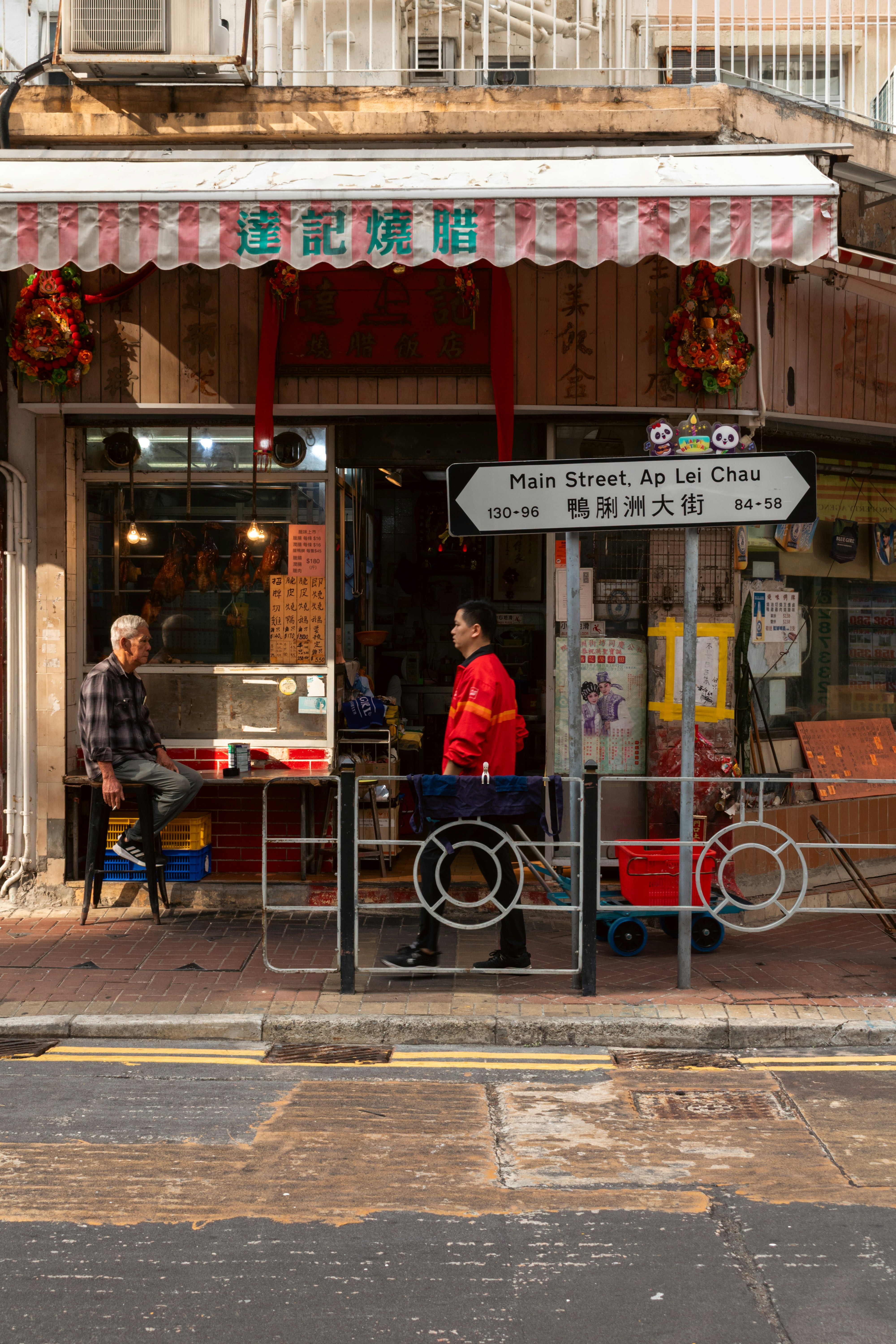 A man sitting on a stool outside a restaurant on Main Street, Ap Lei Chau