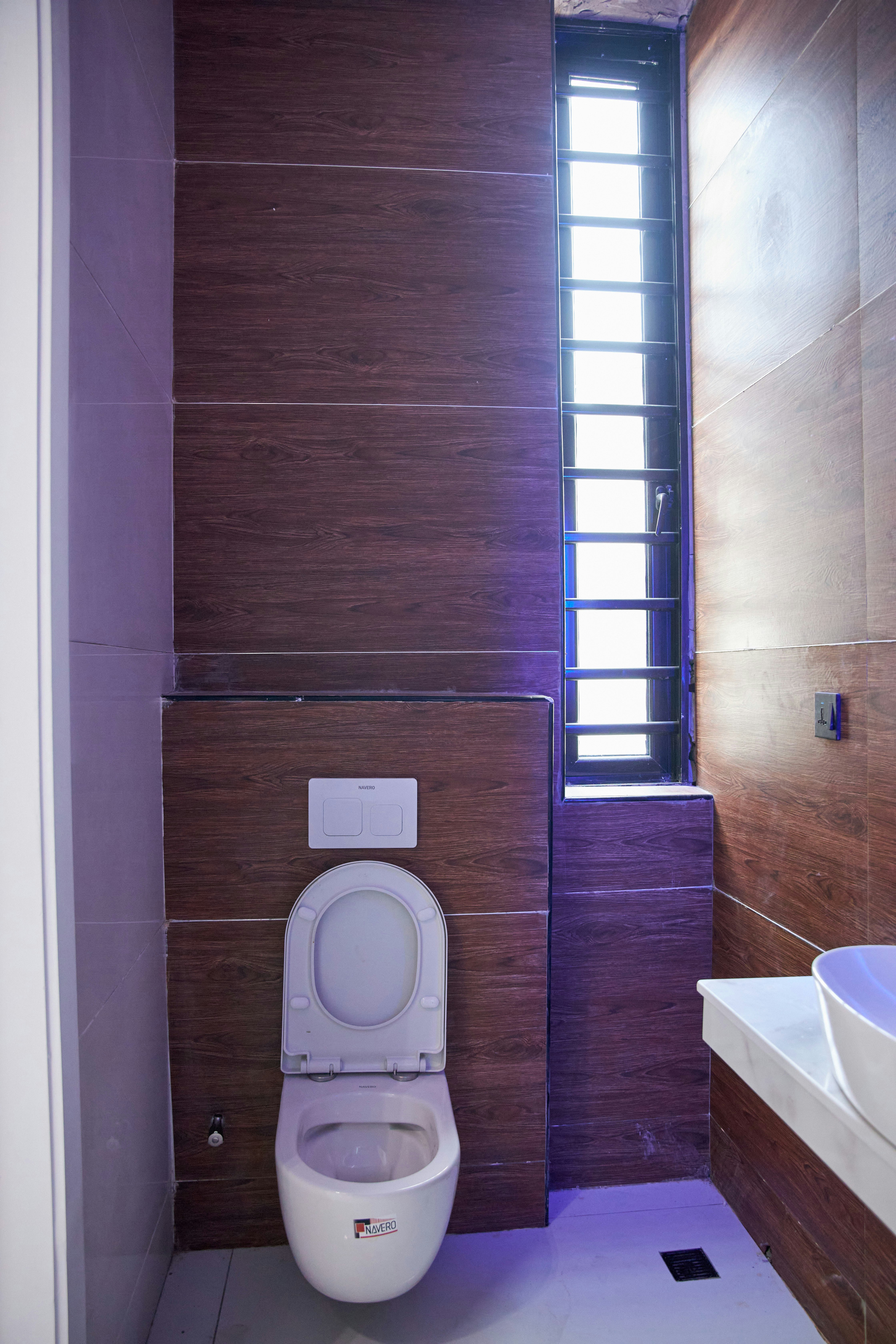 Modern bathroom with wood-look wall tiles, a white toilet, and a tall window