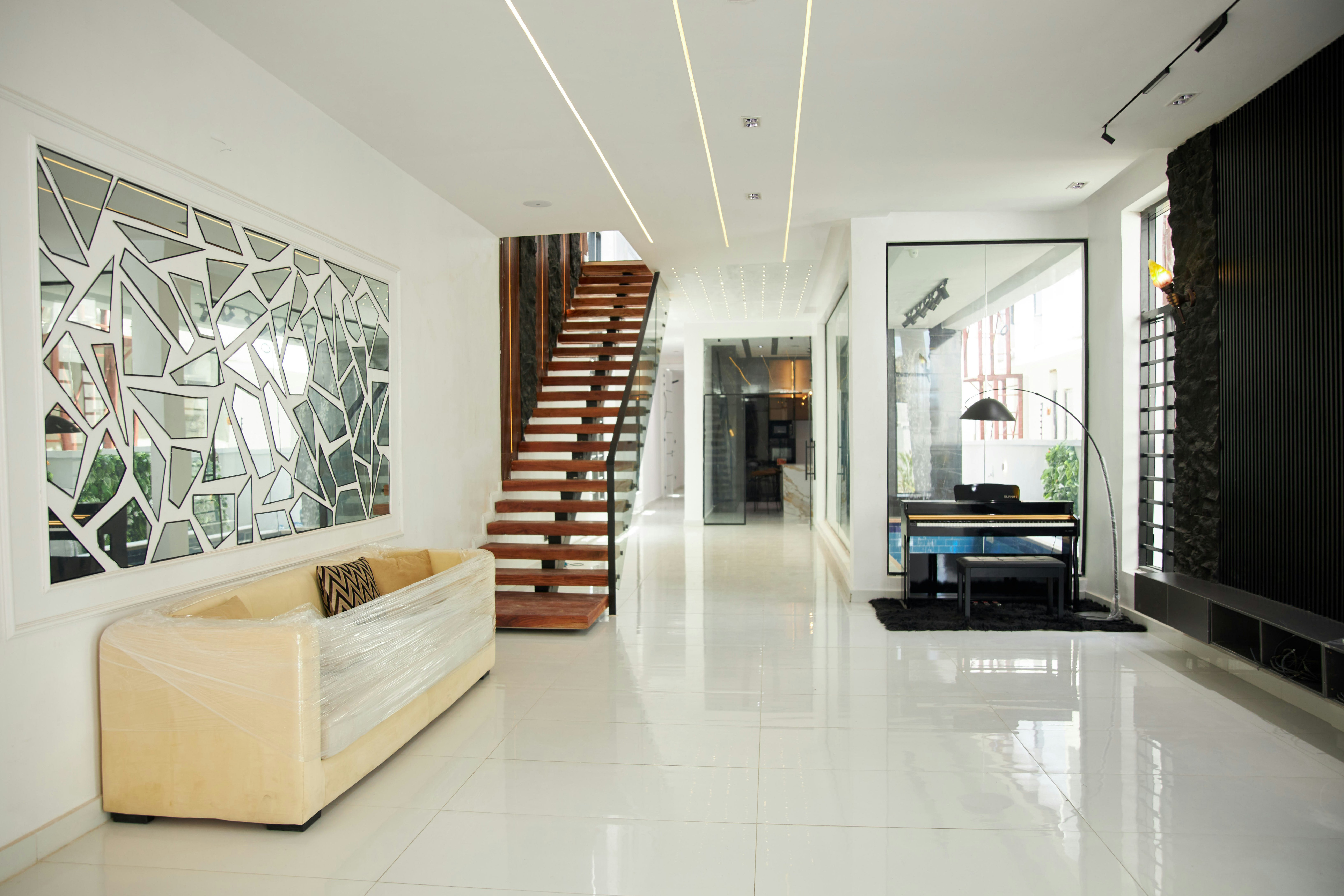 white screen wallpaper - A modern living room with a plastic-wrapped sofa, wooden staircase, and black piano