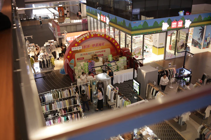 An elevated view of a shopping mall interior with clothing racks and promotional displays