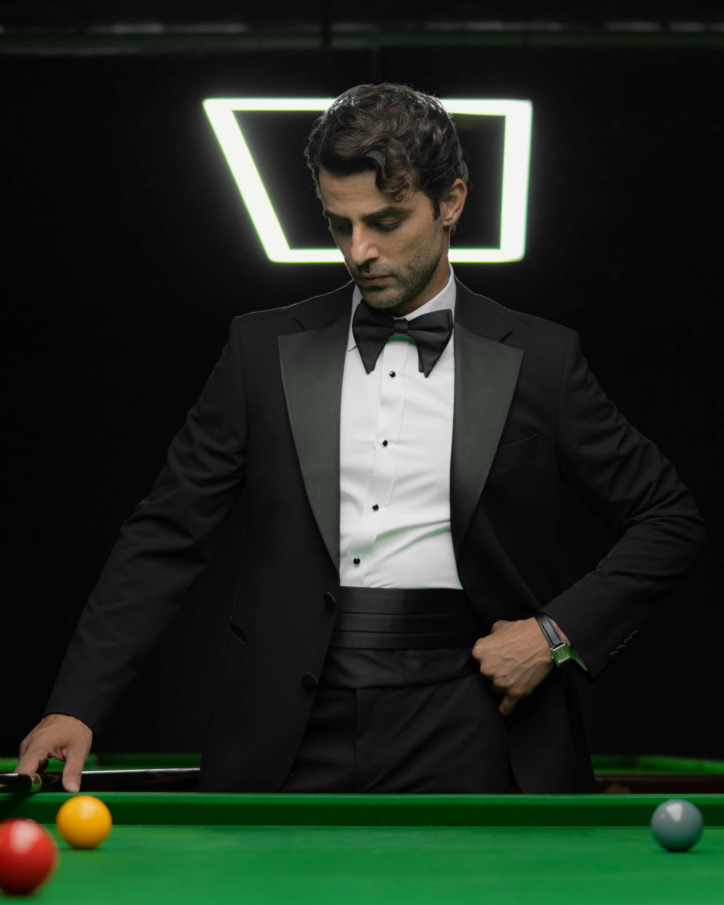 Leaning on a billiard table in black tie