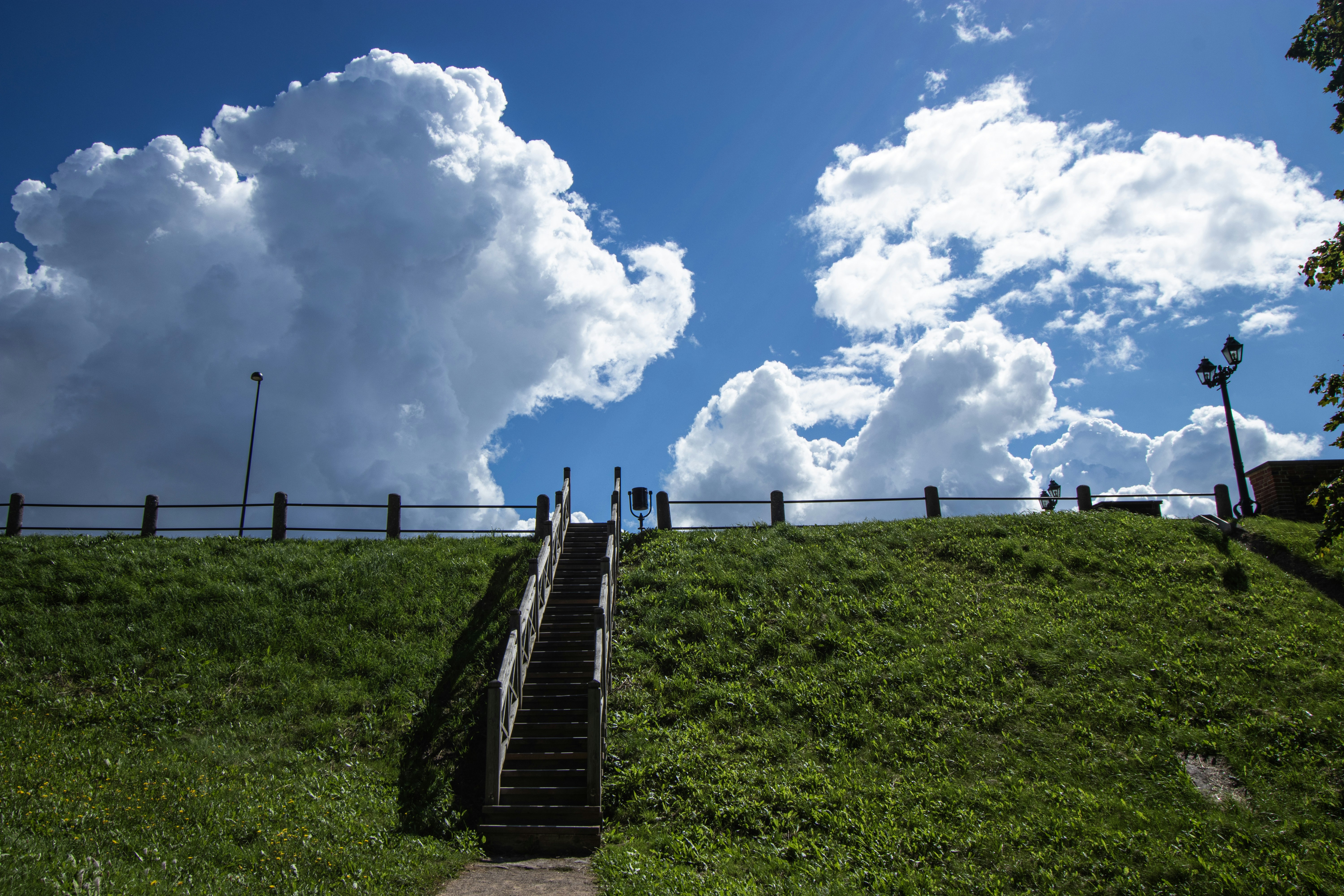 Wooden stairs leading up a grassy hill under a bright blue sky