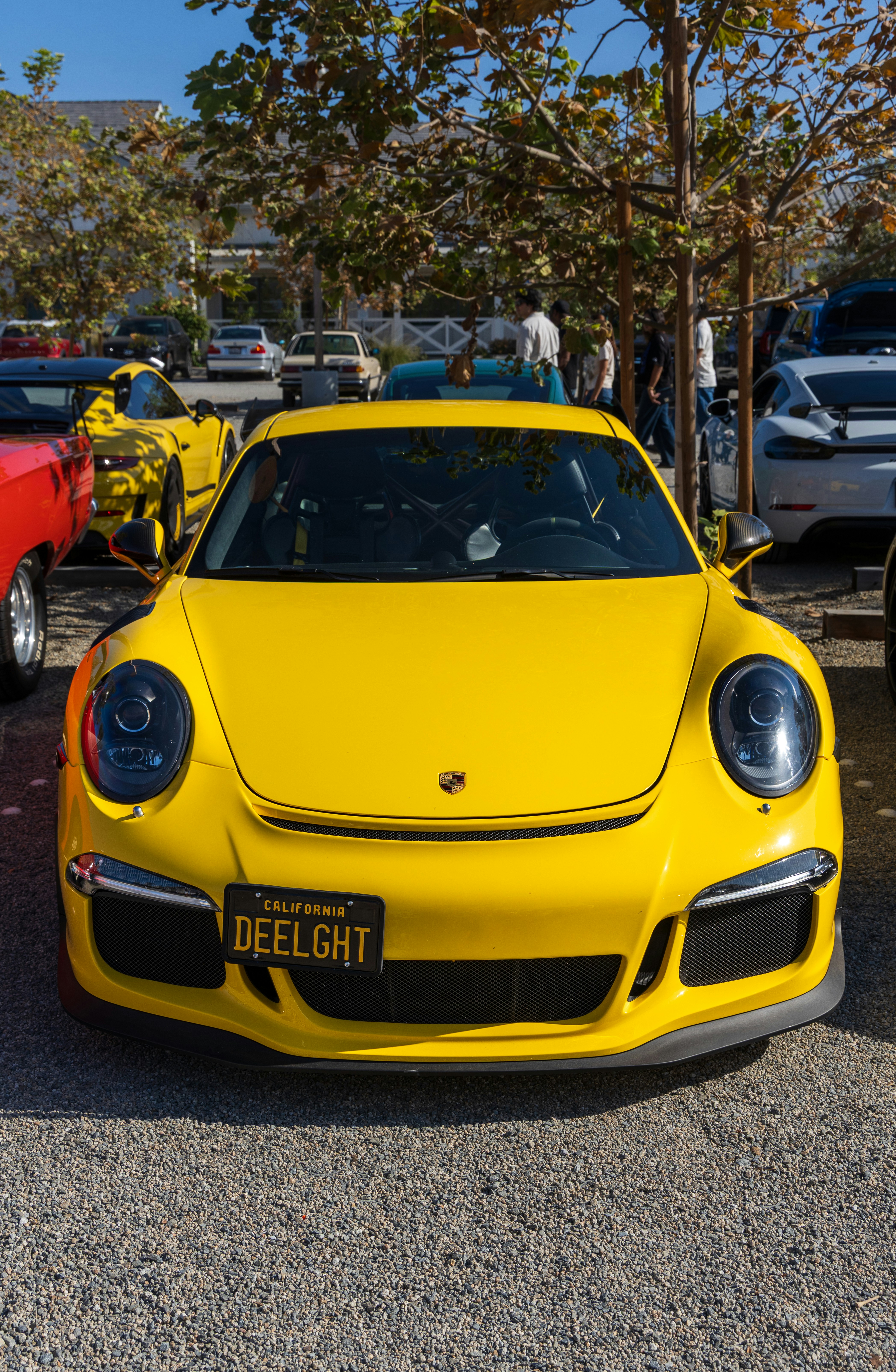 A yellow Porsche sports car with a California license plate in a parking lot.
