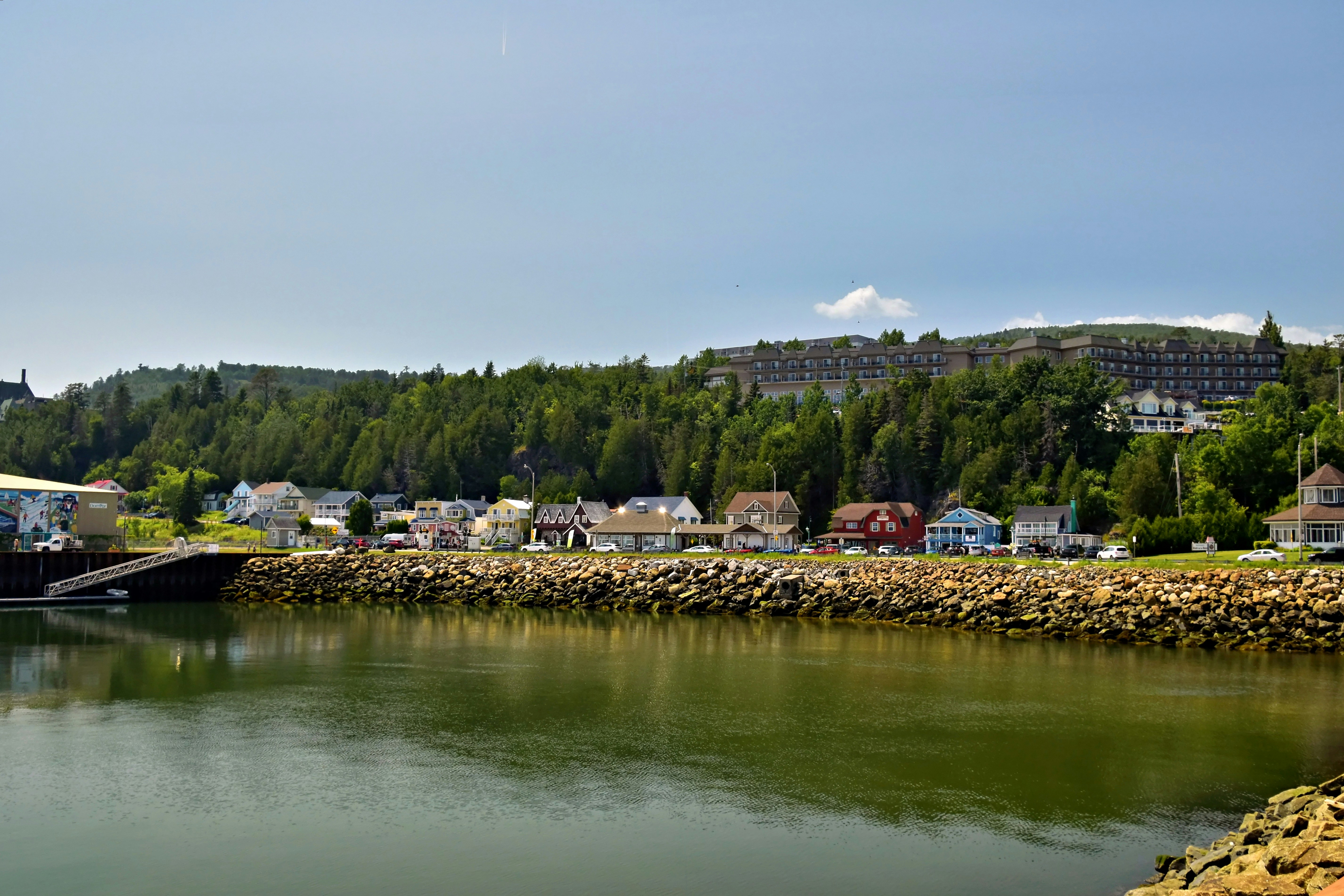 A coastal town with colorful houses along a rocky shoreline and green forest