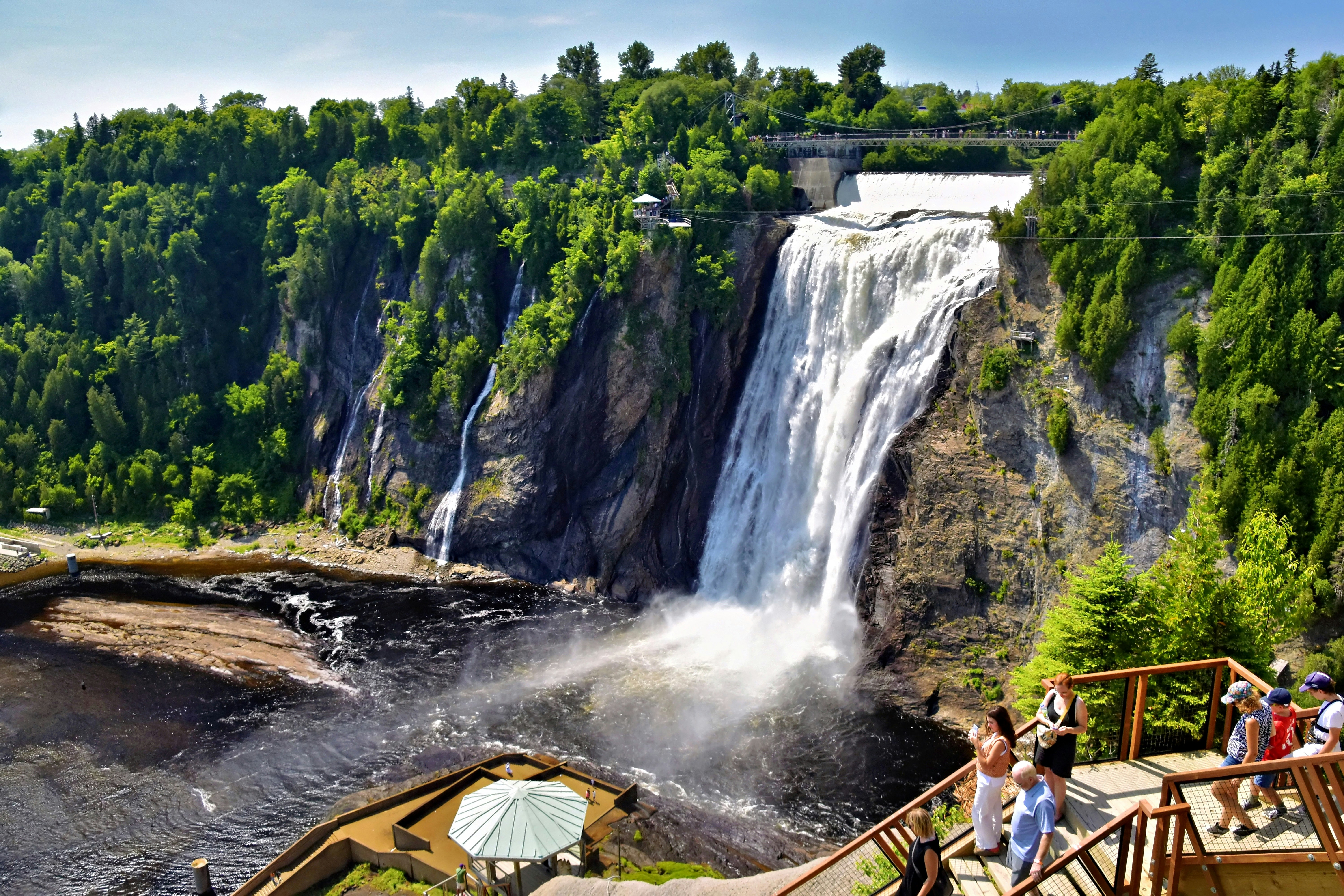A large waterfall cascading over a rocky cliff into a dark river below