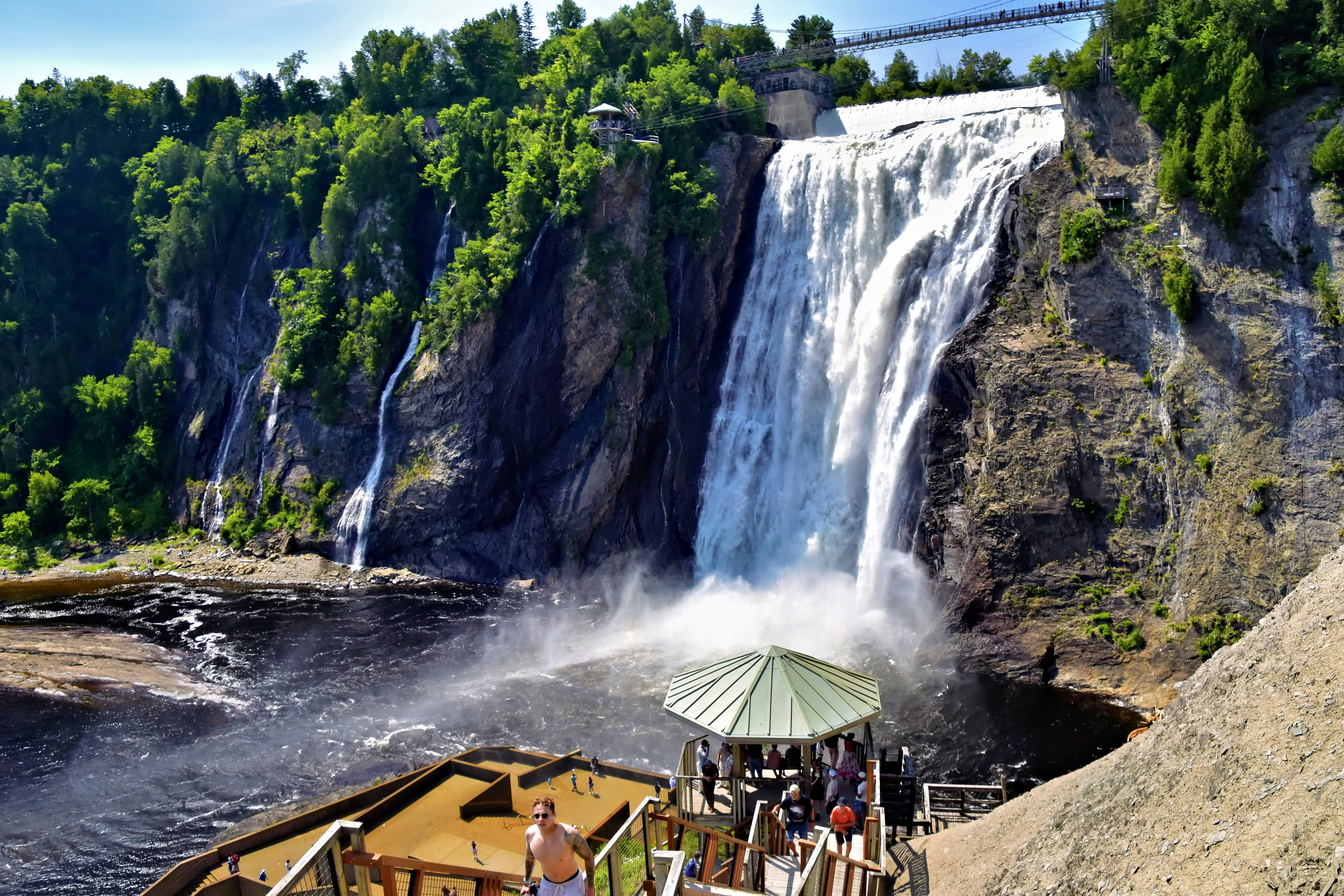 Montmorency Falls cascading down a rocky cliff into a dark river in Quebec
