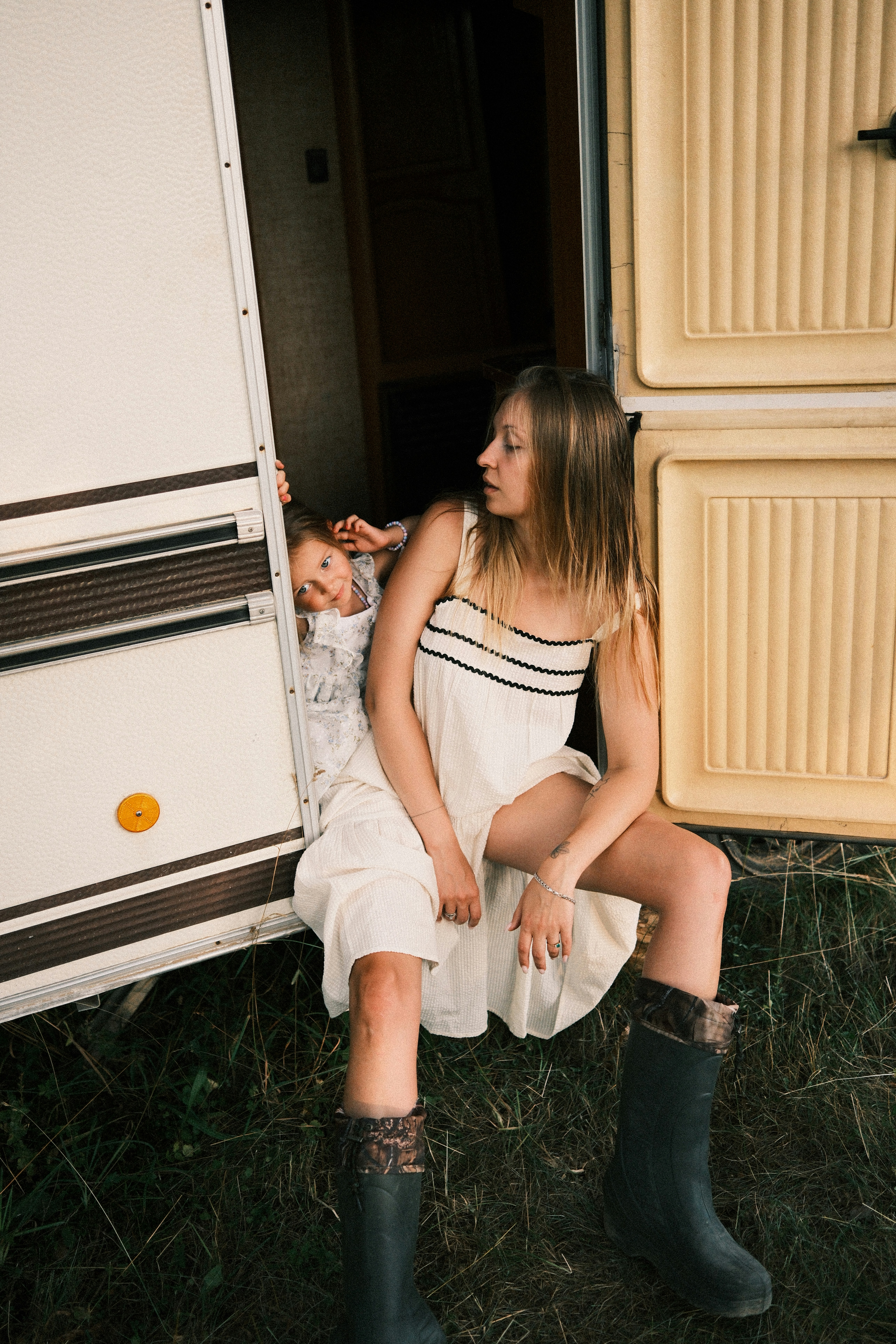 A woman and a child in the doorway of a camper van.