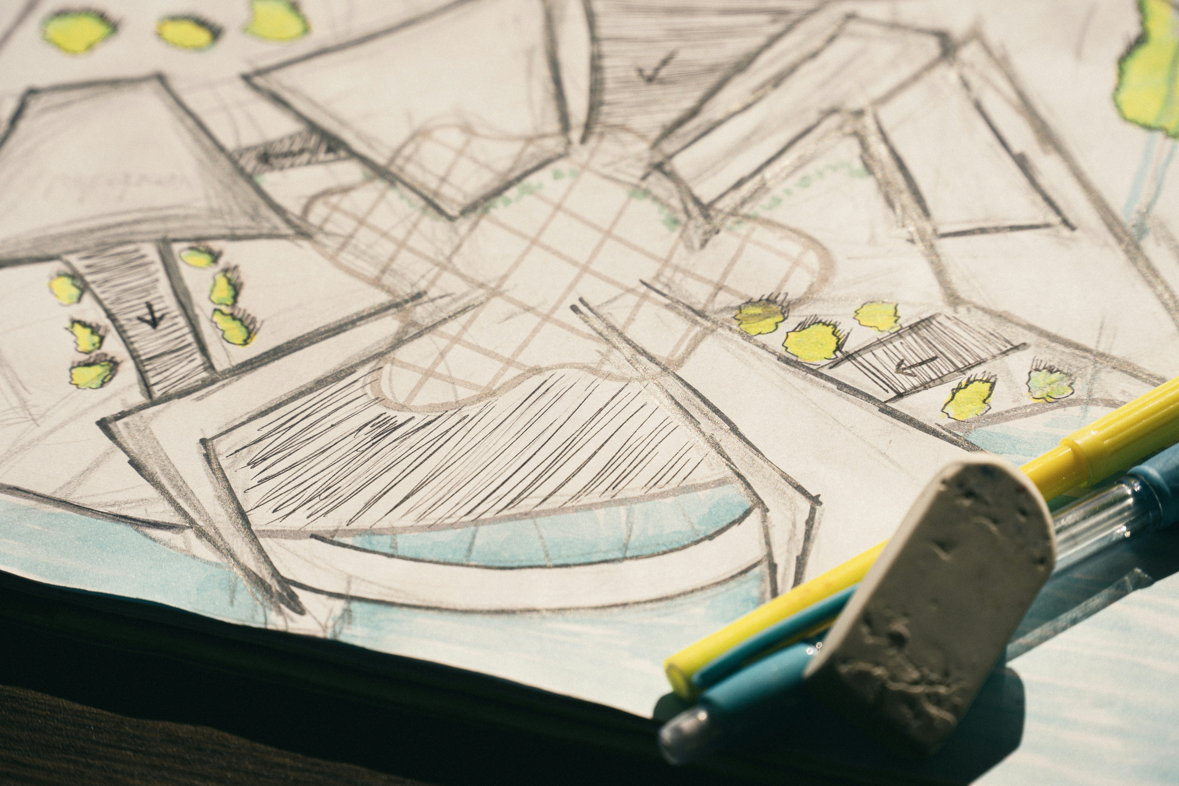 A pencil sketch of a building floor plan with yellow markers and an eraser.