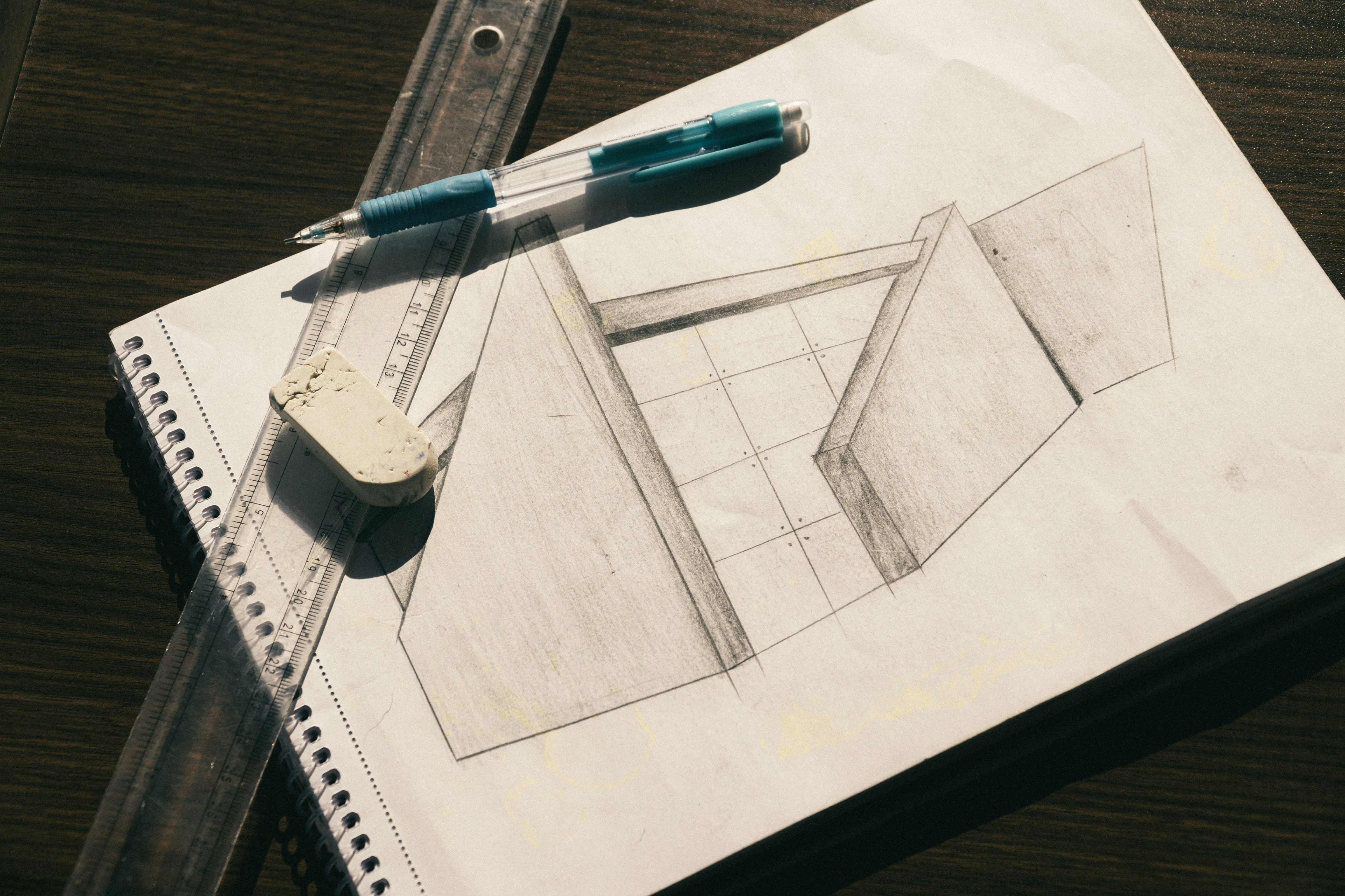 Um esboço a lápis de formas geométricas em papel com uma régua e borracha.