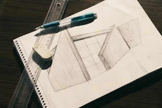 A pencil sketch of geometric shapes on paper with a ruler and eraser