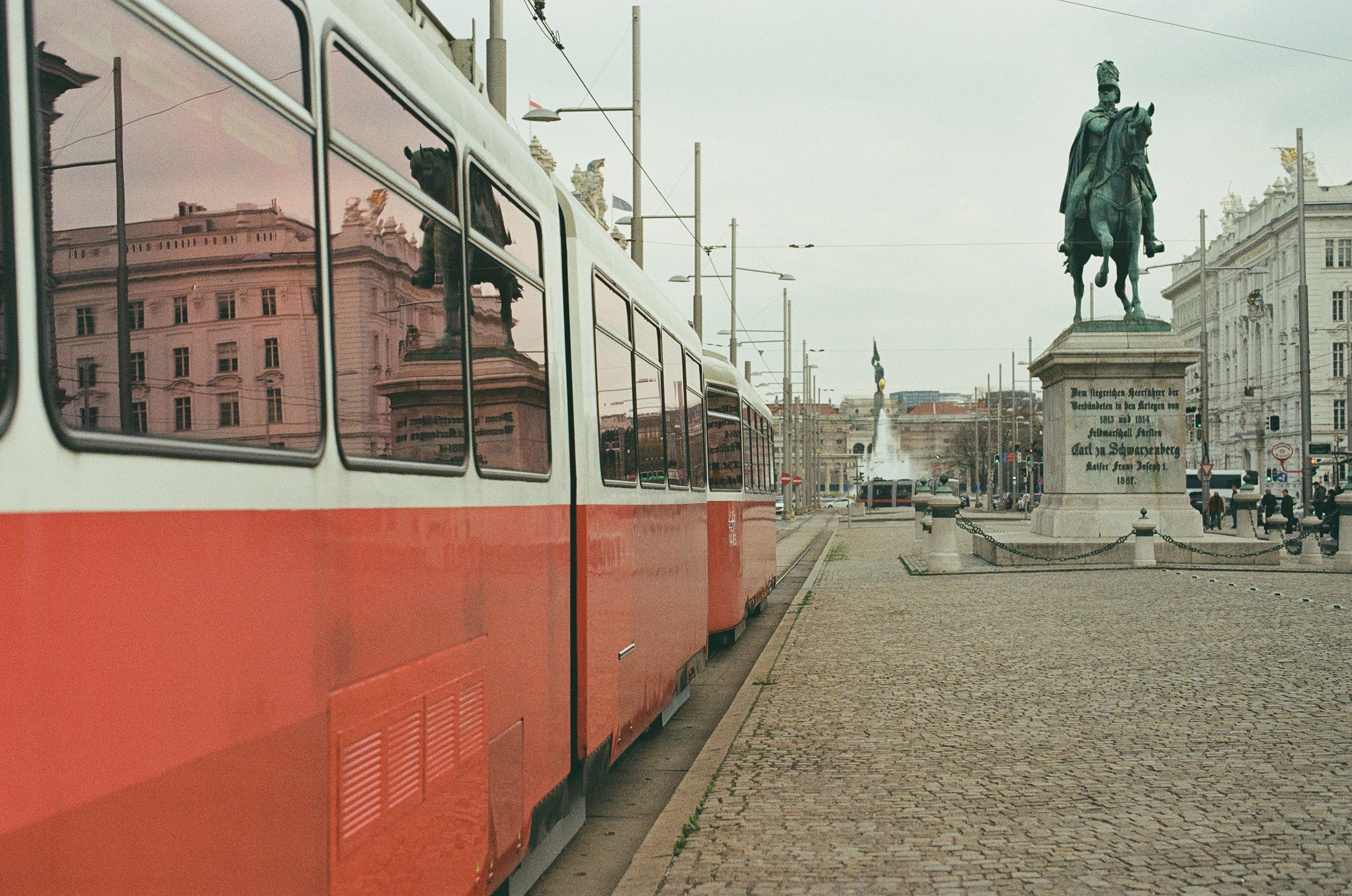 A red and white tram beside the Schwarzenberg monument in Vienna, Austria
