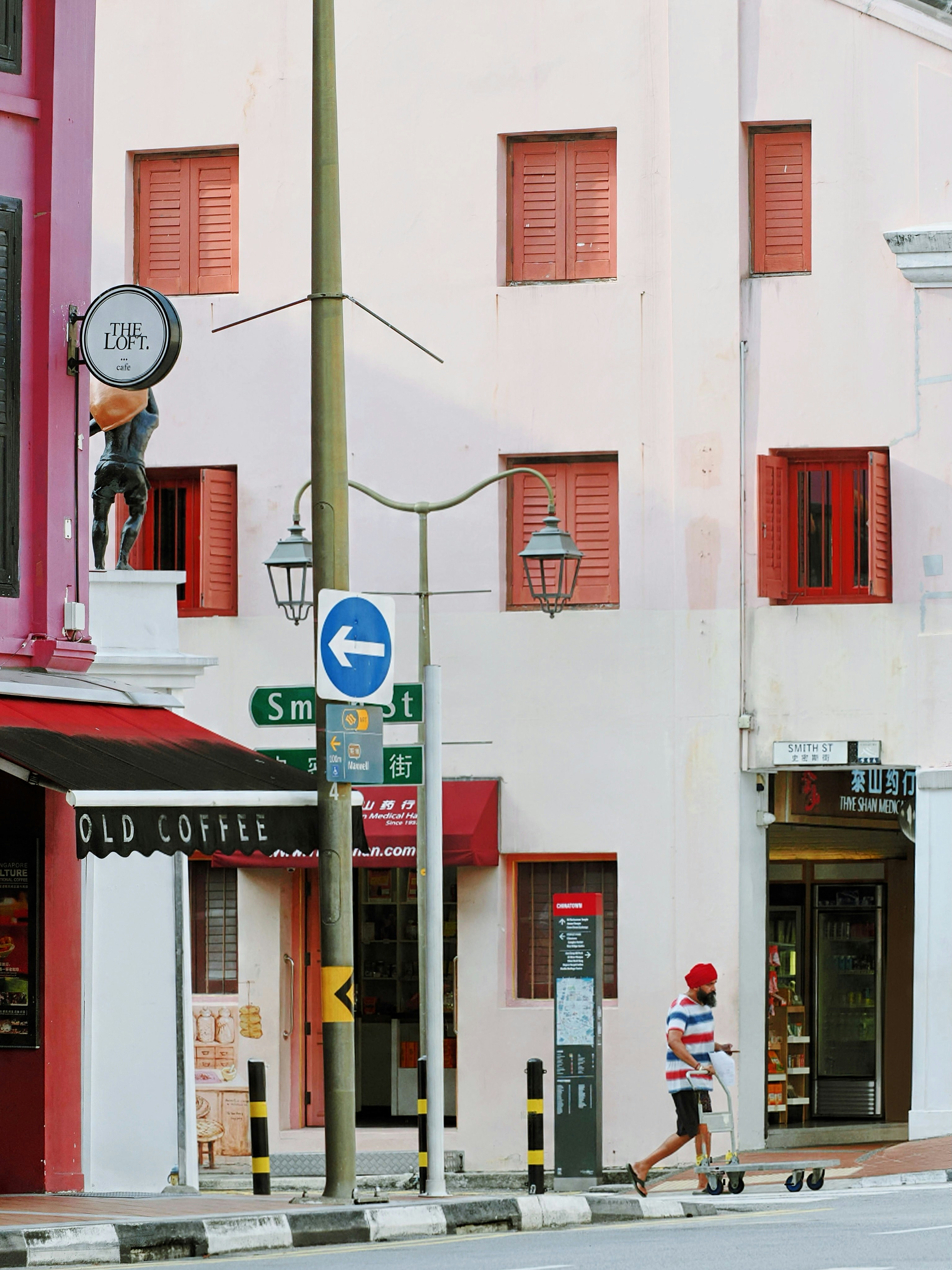 A person in a red turban pushing a cart on Smith Street in Singapore.