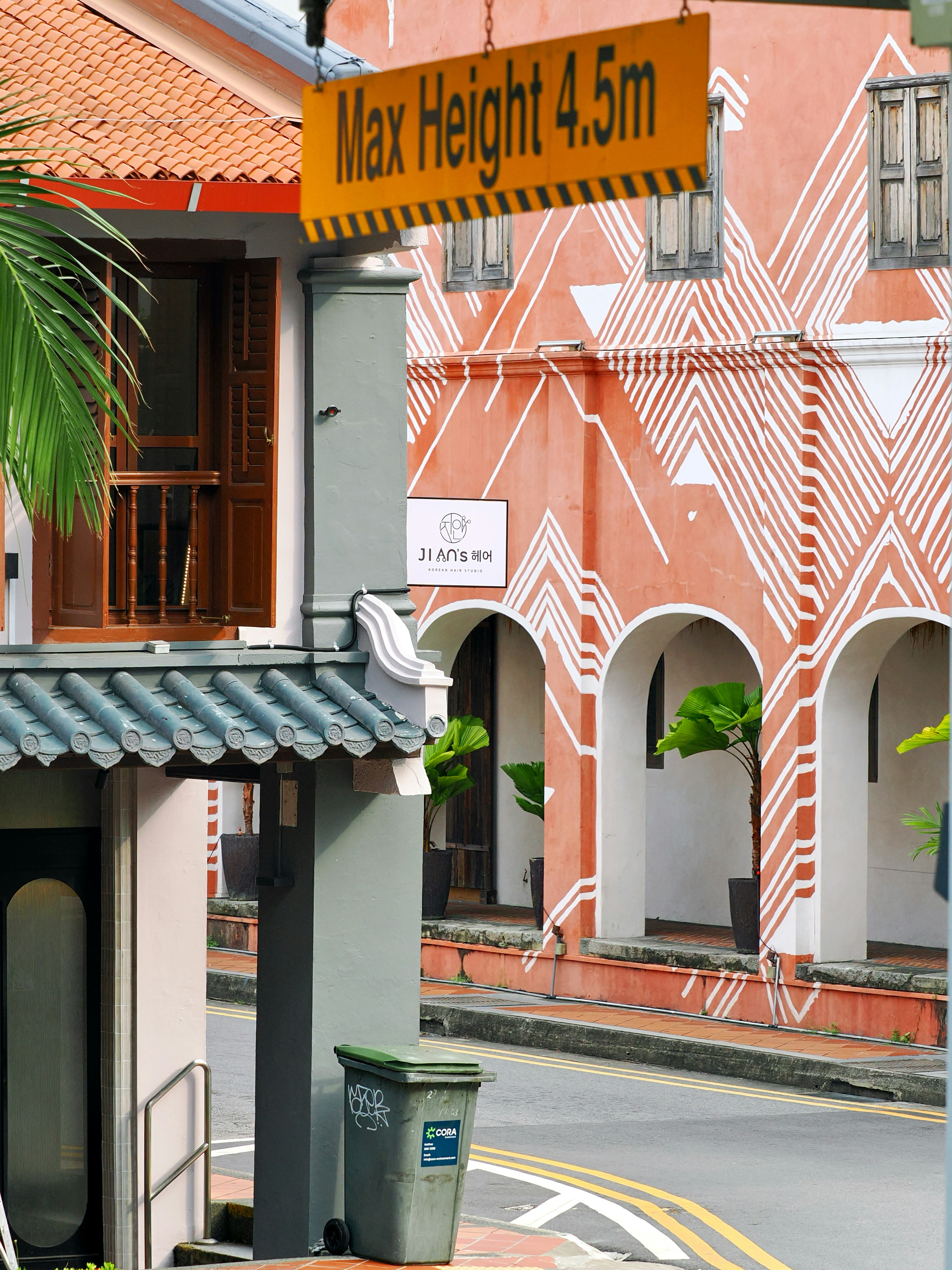 A street with a terracotta building featuring white geometric patterns and arched doorways.