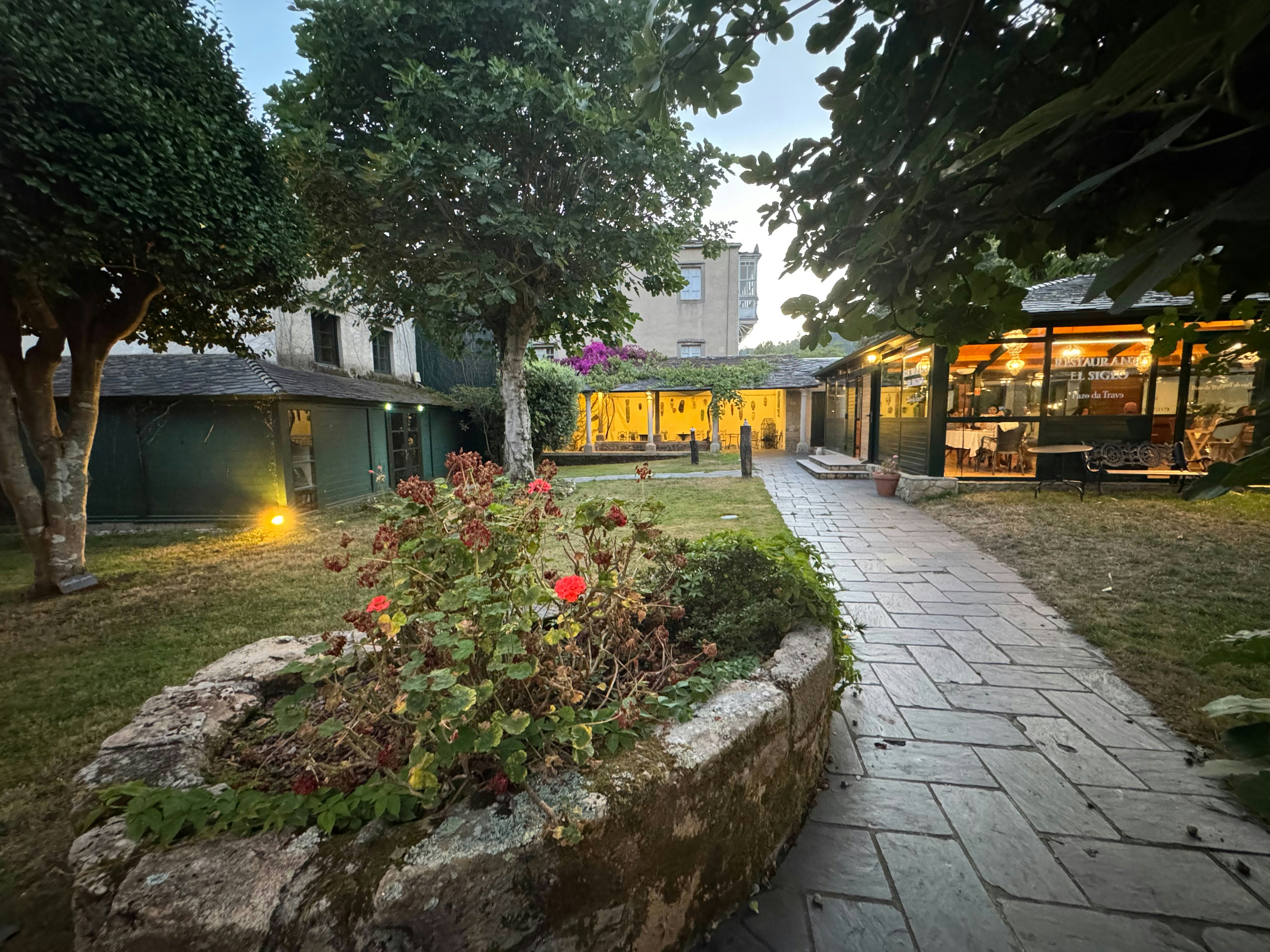 A stone planter with red flowers in a courtyard beside a stone path.