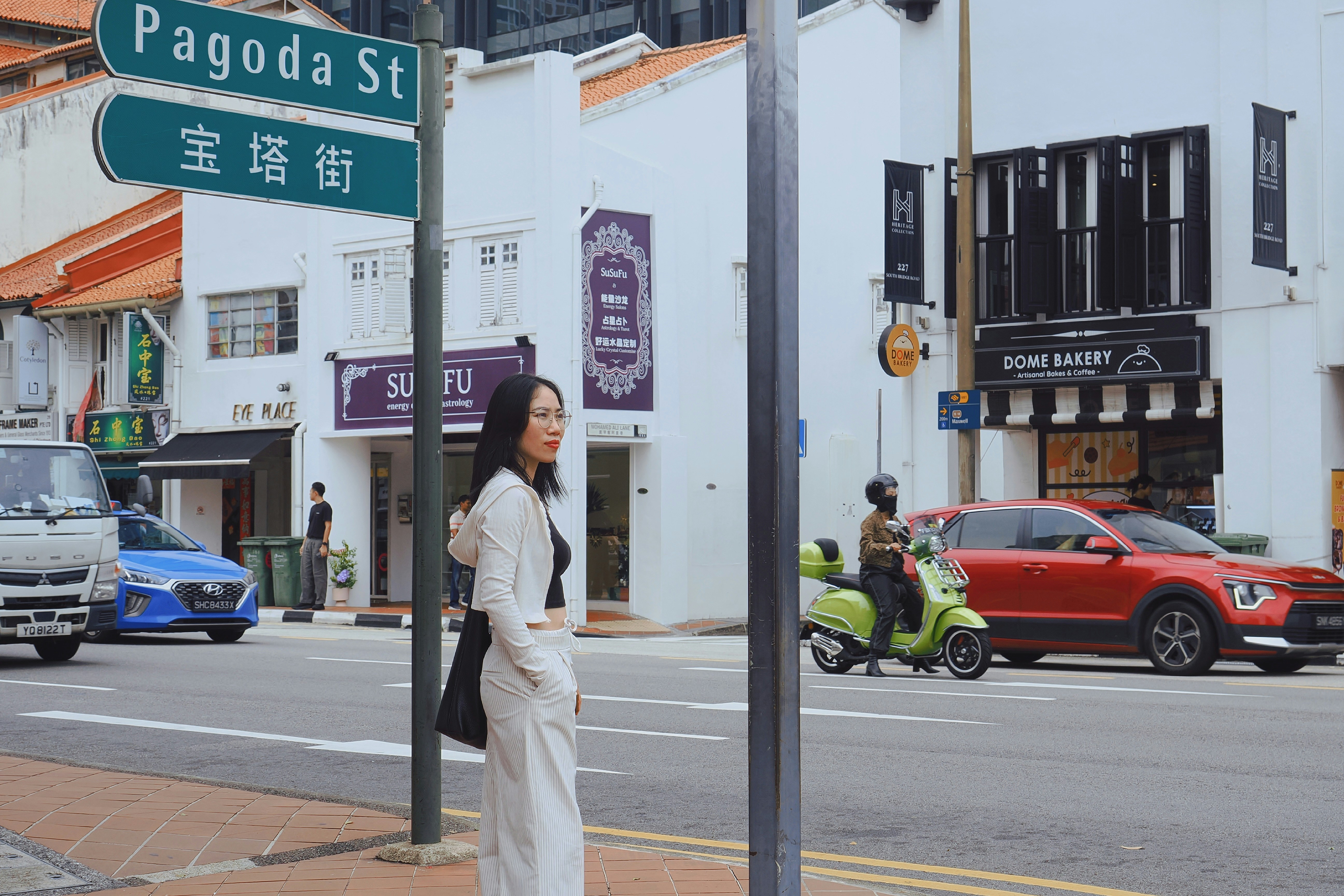 A woman standing on Pagoda Street in Singapore near a green street sign.